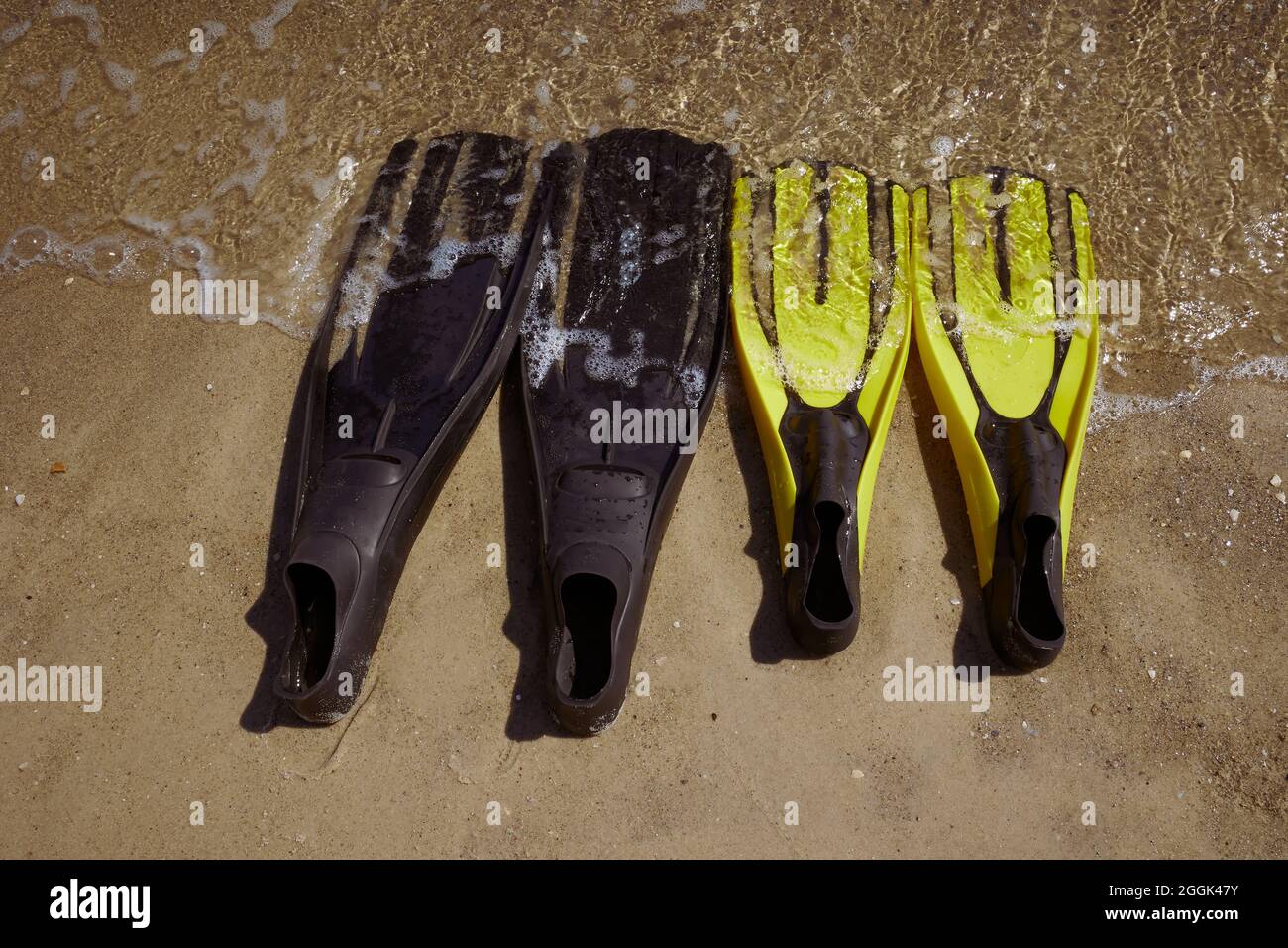 Nahaufnahme von zwei Flossen-Paaren, die in der Brandung am Meer liegen. Sonniger Tag, Odessa Ukraine. Stockfoto