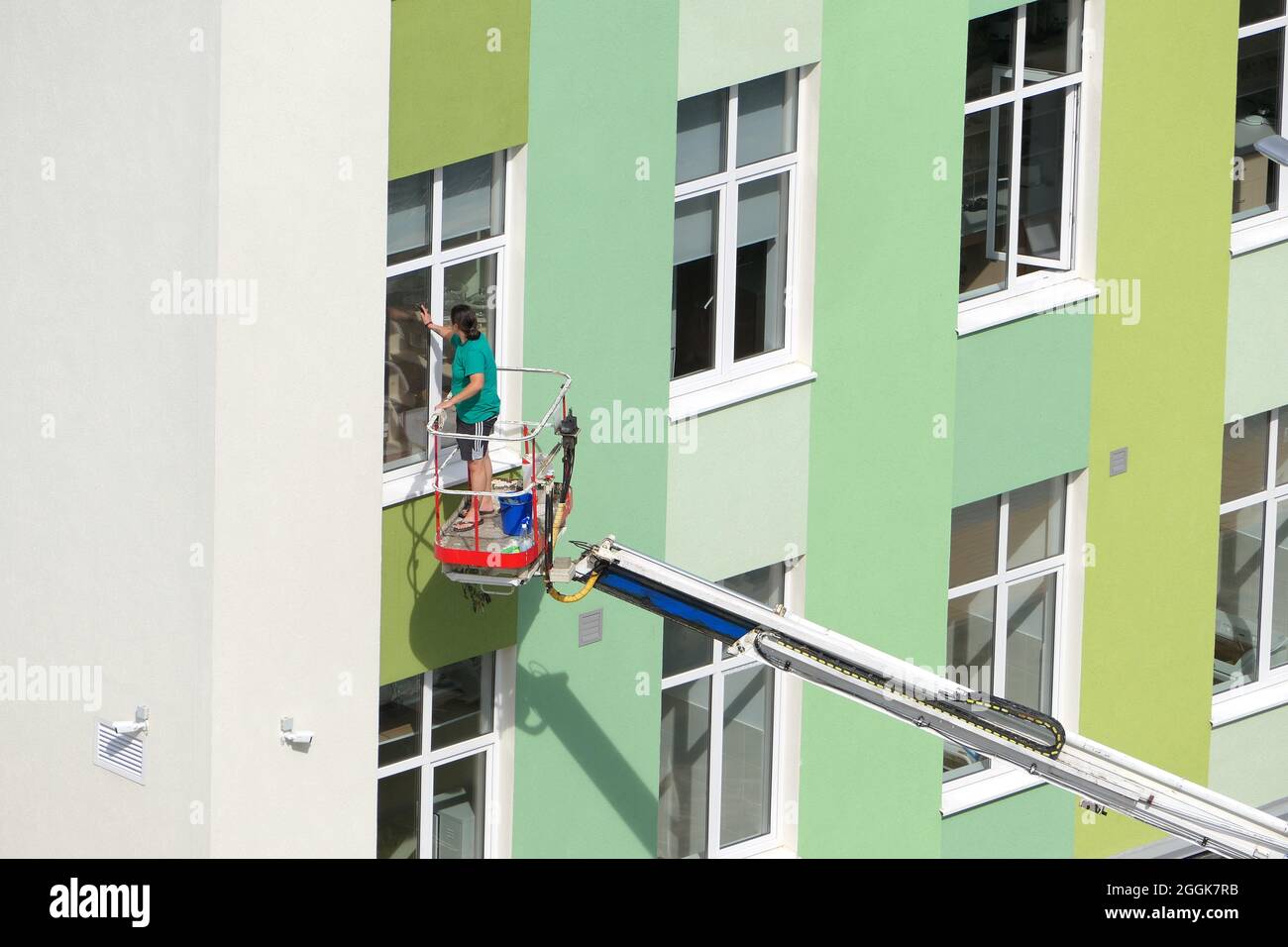 Nischni Nowgorod, Russland, Gagarin Avenue 101 b, Schule Nr. 34. 08.26.2021. Eine Frau, Angestellte einer Reinigungsfirma, wäscht die Fenster des Gebäudes Stockfoto