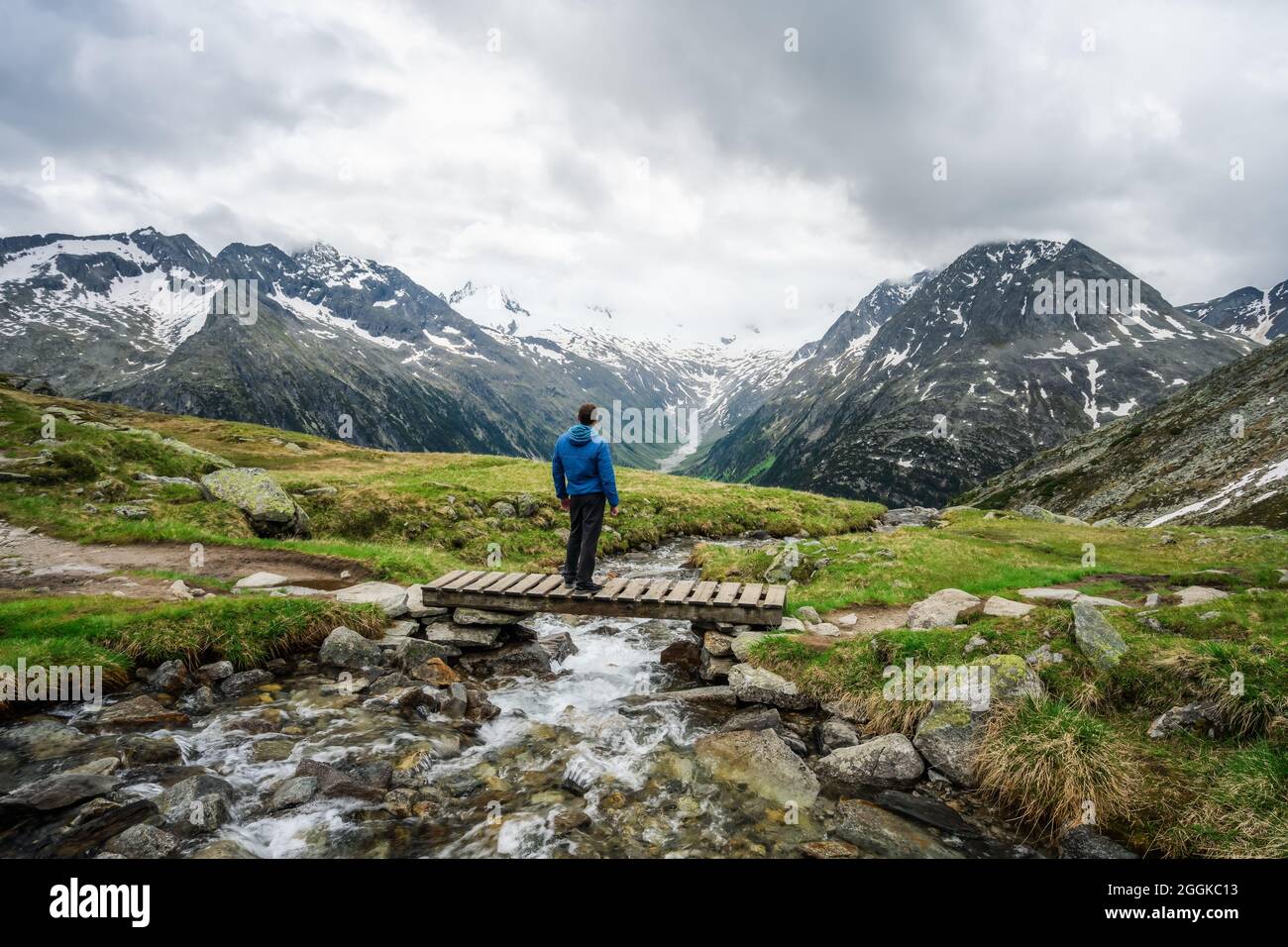 Mann Wanderer auf kleiner Brücke über Berg Fluss am Schlegeis See, Zillertaler Alpen, Österreich ruhen Stockfoto