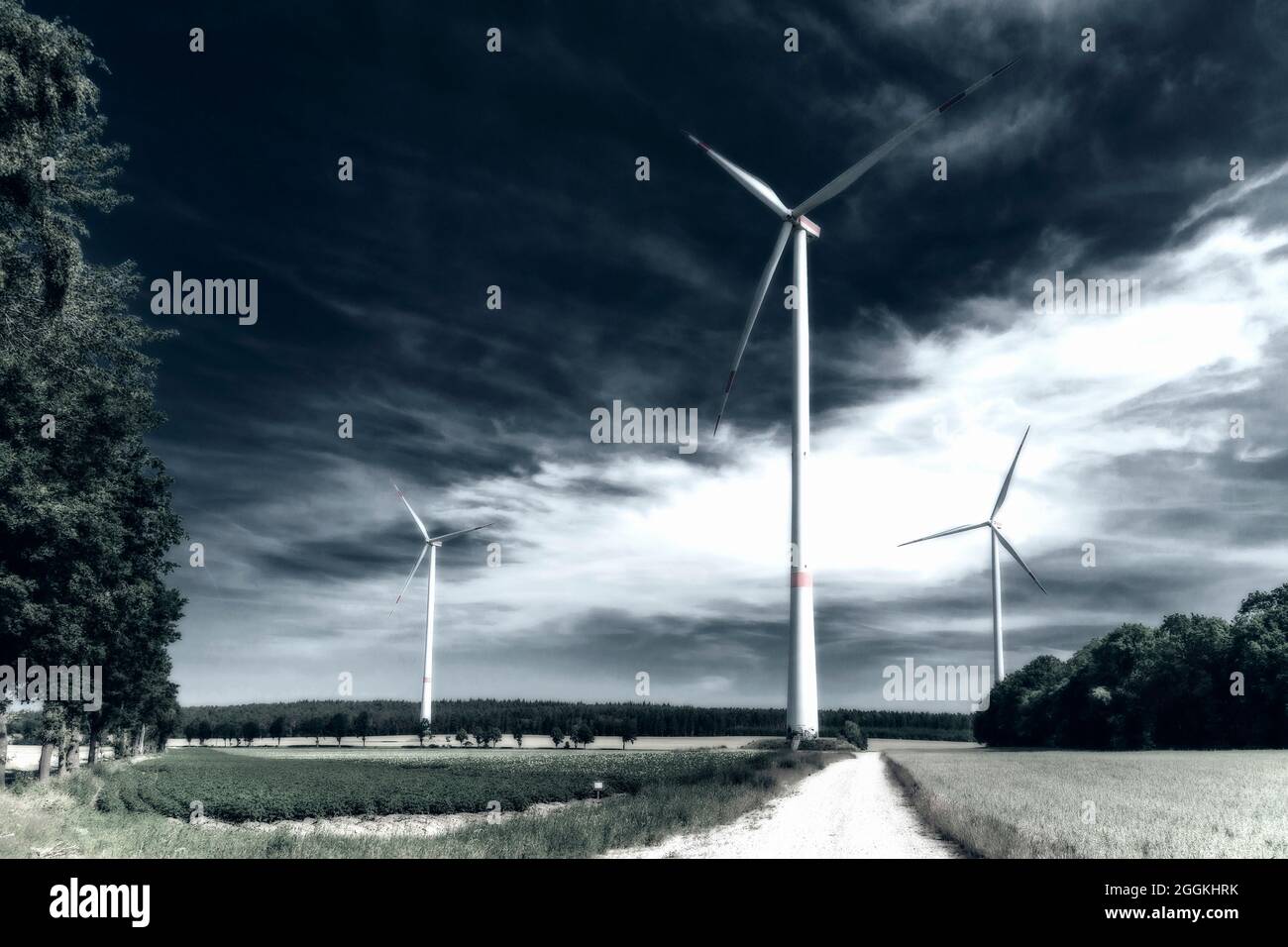 Energiewirtschaft, Windenergie, Windpark, drei-Blatt-Windkraftanlagen, dunkler Himmel mit Lichtfleck, reduzierte Farbe Stockfoto