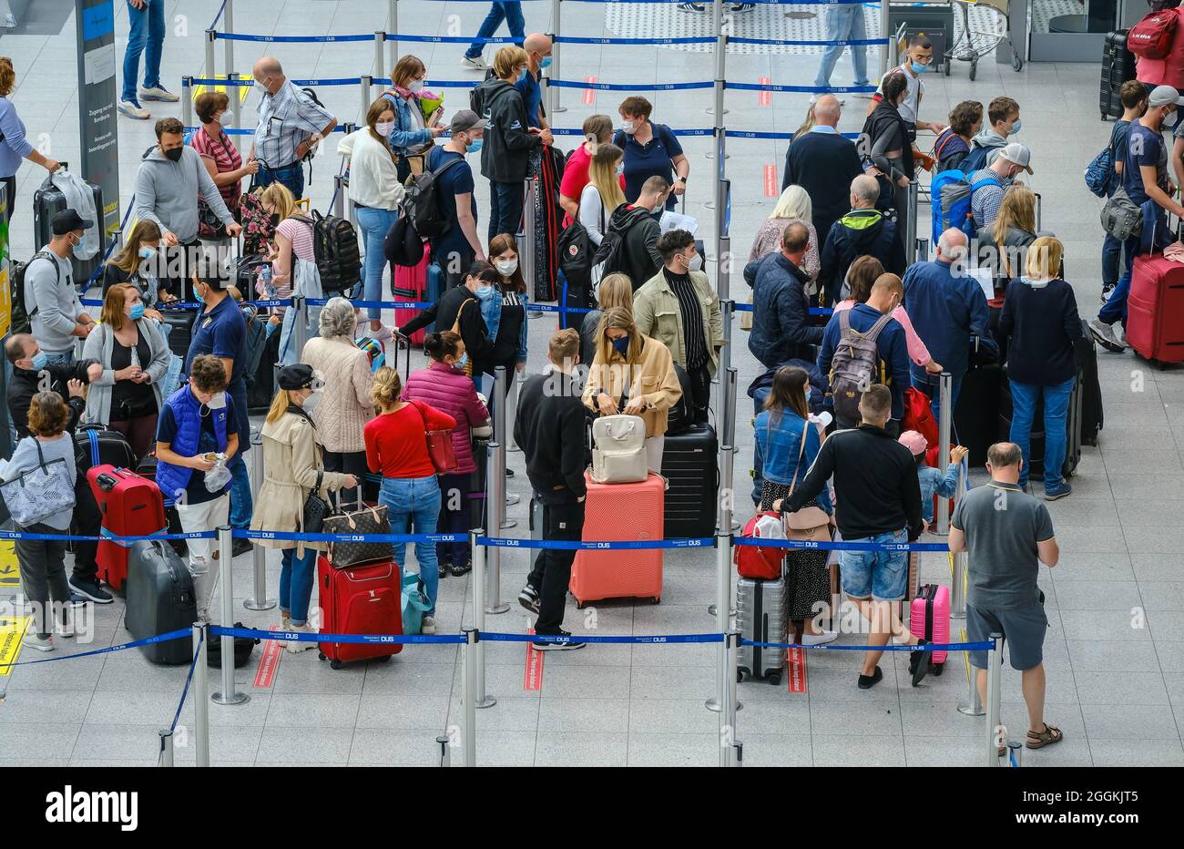 Düsseldorf, Nordrhein-Westfalen, Deutschland - Flughafen Düsseldorf, Urlaubsstart in NRW stehen Urlauber in Zeiten der Coronapandemie mit Koffern in der Schlange am Check-in-Schalter auf dem Weg in den Sommerurlaub. Stockfoto