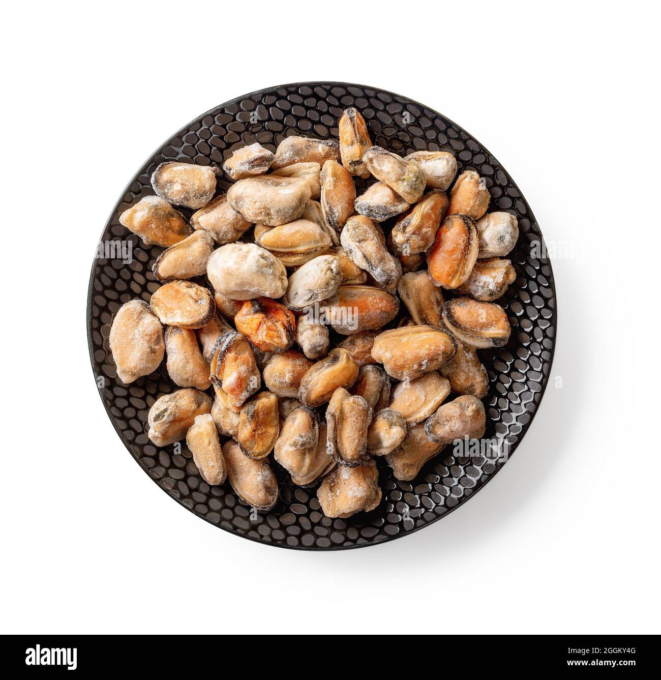 Gefrorenes gekochtes Muschelfleisch auf einer schwarzen, strukturierten Keramikplatte, isoliert auf weißem Hintergrund. Geschälte Muscheln als Zutat für leckere Meeresfrüchte-Rezepte. Stockfoto