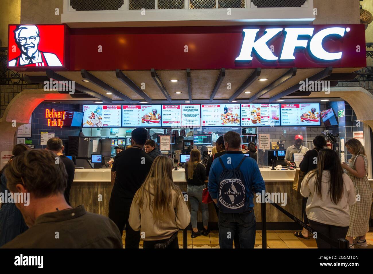 Im KFC Kentucky Fried Chicken Fast Food Outlet im Trafford Centre, Manchester, England, Großbritannien, stehen die Leute Schlange, um Lebensmittel abzuholen Stockfoto