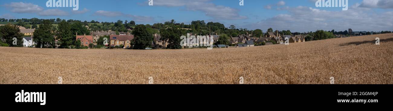 Panorama von Chipping Campden, Gloucestershire, Großbritannien am Horizont. Fotografiert im Spätsommer mit einem Weizenfeld im Vordergrund. Stockfoto