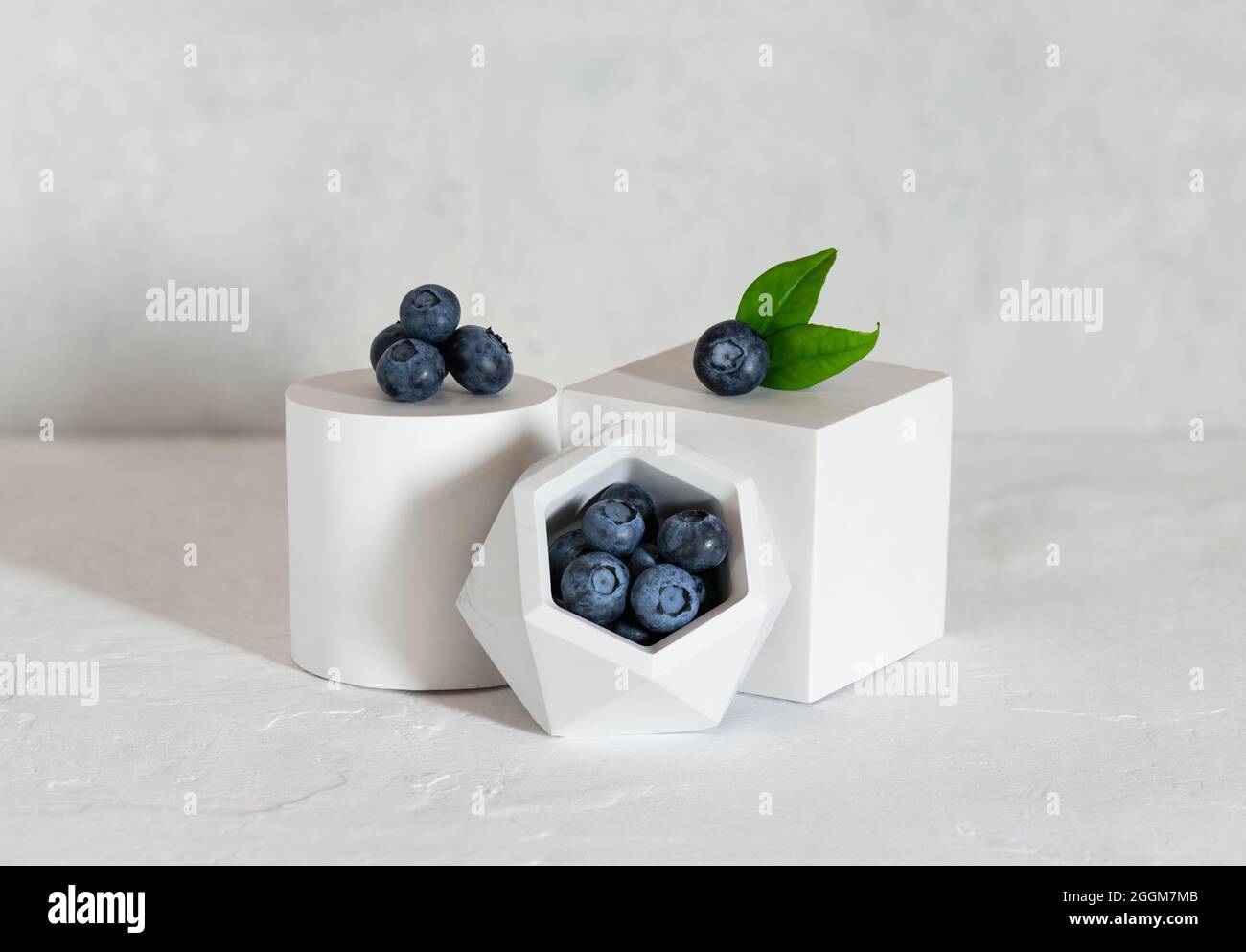 Heidelbeeren stehen auf einem grauen Betongrund. Reife, frische, blaue Beeren auf dem Podium. Gesundes Bio-Food-Konzept. Stockfoto