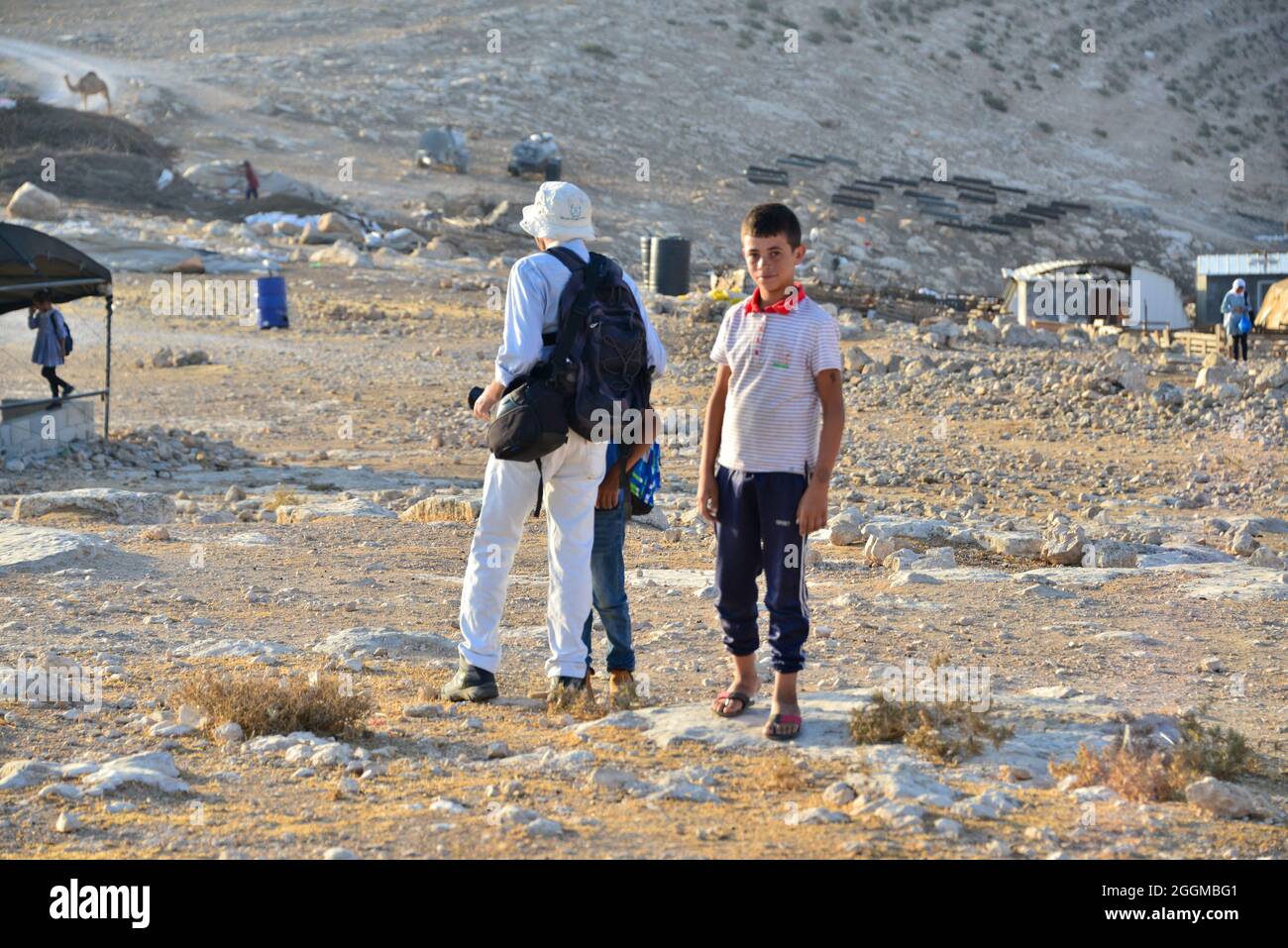 Seit 2004 gehen die Kinder aus dem Dorf Tuba zur Schule im nahegelegenen Dorf at-Tuwani, 2.6 km entfernt - während sie von einem jüdischen Aktivisten und einem Fahrzeug der israelischen Streitkräfte begleitet werden, um sie vor gewalttätigen Angriffen der religiösen jüdischen Siedler aus dem illegalen Außenposten der Maon Farm zu schützen, die auf dem Weg zur Schule gefunden wird. Palästina / Israel, südlich von Hebron. August 2021. (Foto von Matan Golan/Alamy Live News) Stockfoto