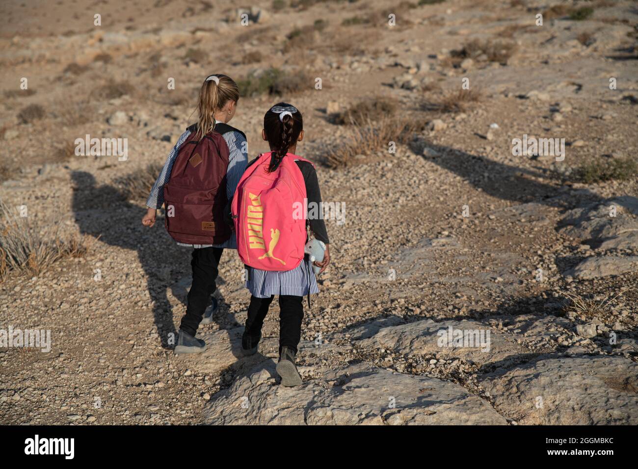 Seit 2004 gehen die Kinder aus dem Dorf Tuba zur Schule im nahegelegenen Dorf at-Tuwani, 2.6 km entfernt - während sie von einem jüdischen Aktivisten und einem Fahrzeug der israelischen Streitkräfte begleitet werden, um sie vor gewalttätigen Angriffen der religiösen jüdischen Siedler aus dem illegalen Außenposten der Maon Farm zu schützen, die auf dem Weg zur Schule gefunden wird. Palästina / Israel, südlich von Hebron. August 2021. (Foto von Matan Golan/Alamy Live News) Stockfoto