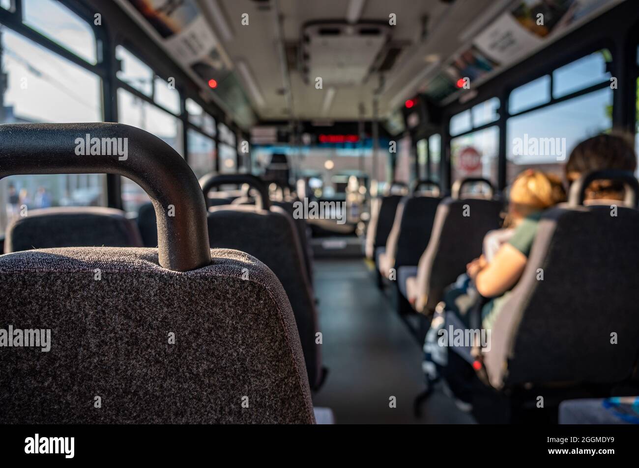 Konzentrieren Sie sich auf einen leeren Sitzplatz in einem Bus mit nur einer alleinerziehenden Mutter und einem Kind in der Ferne. Stockfoto