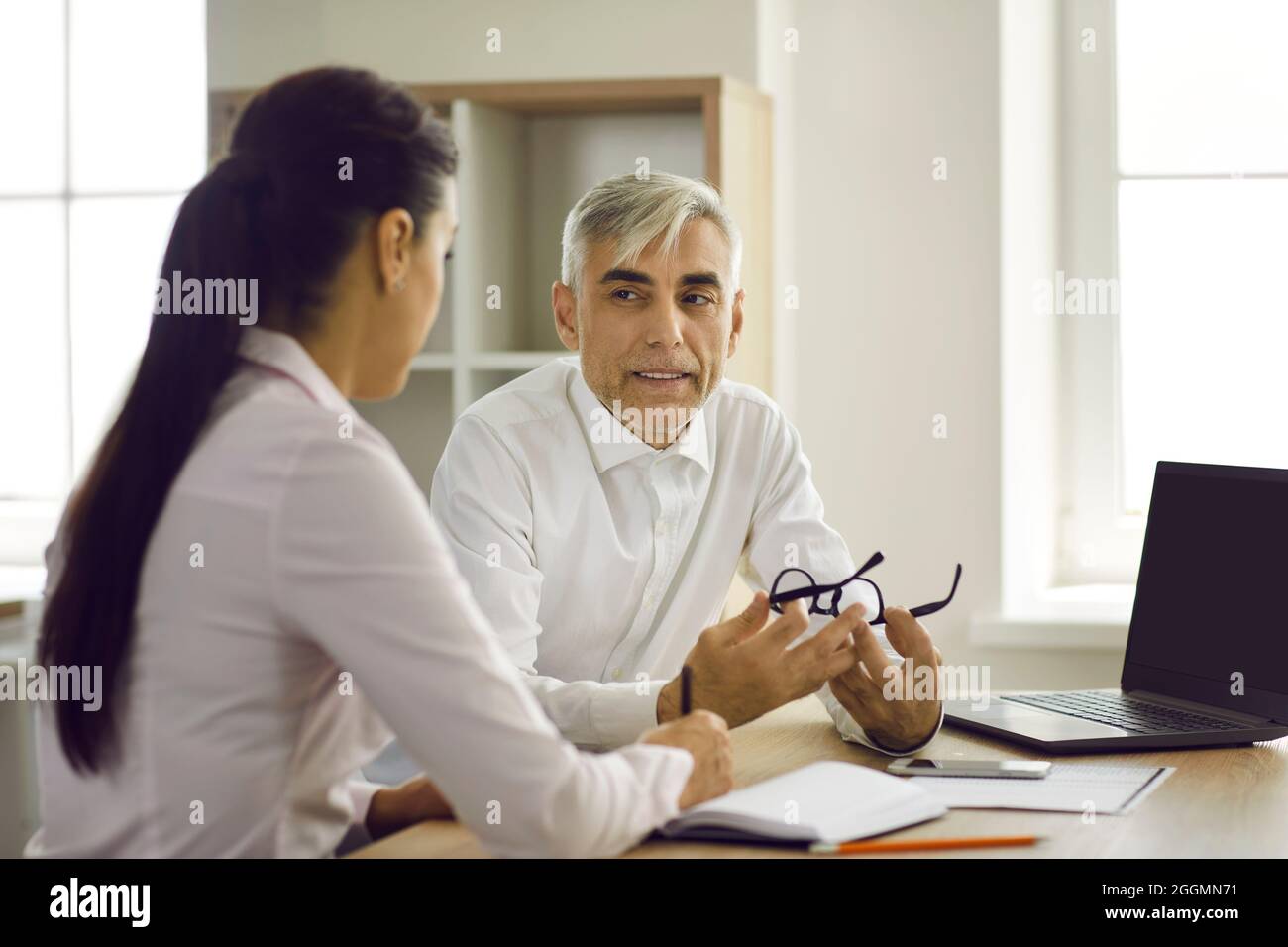 Senior Businessman im Büro diskutiert mit seiner jungen Partnerin ein neues Geschäftsprojekt. Stockfoto