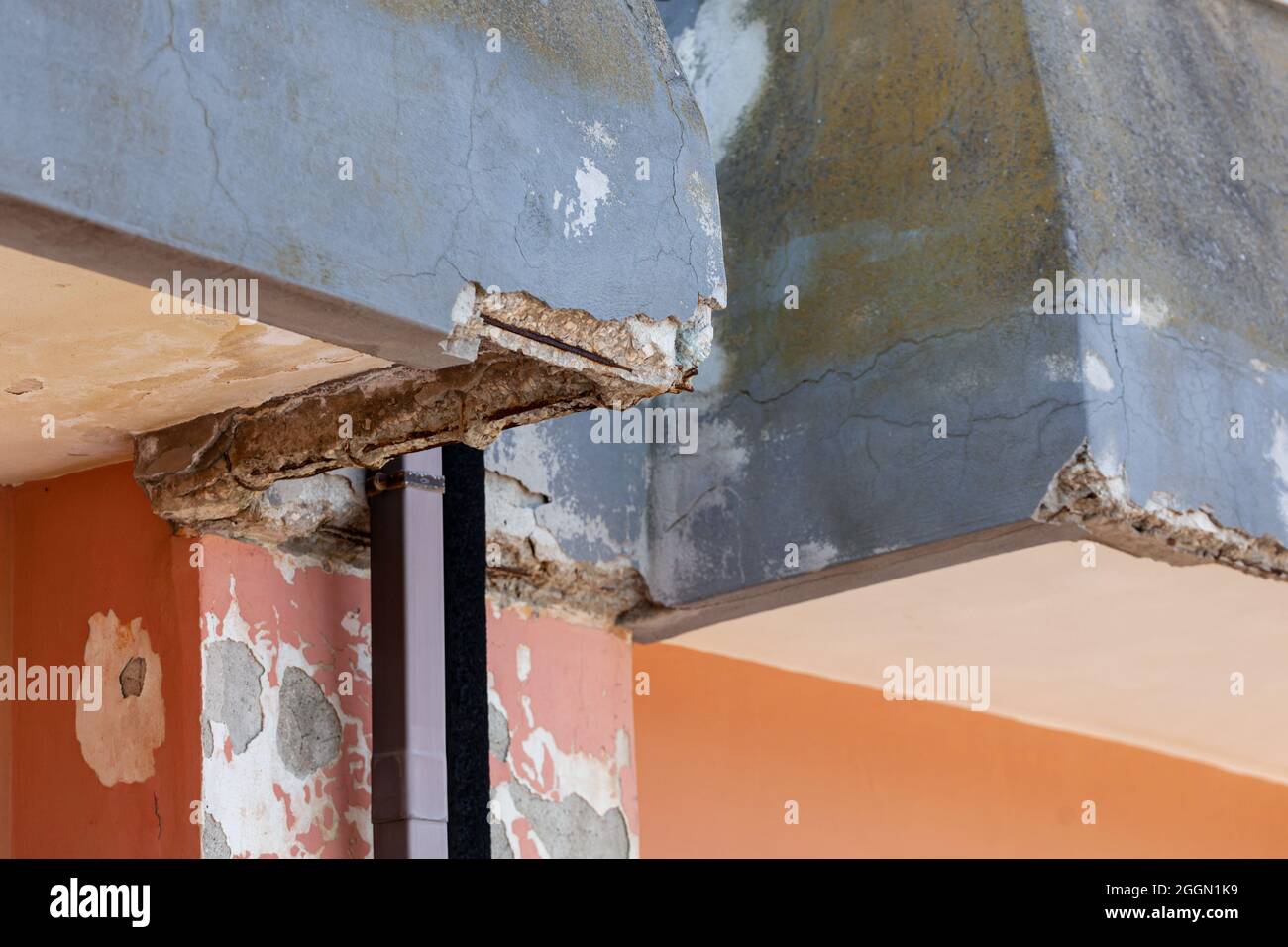 Wand mit rissigem Beton und rostigen Eisen, die renoviert werden müssen. Stockfoto