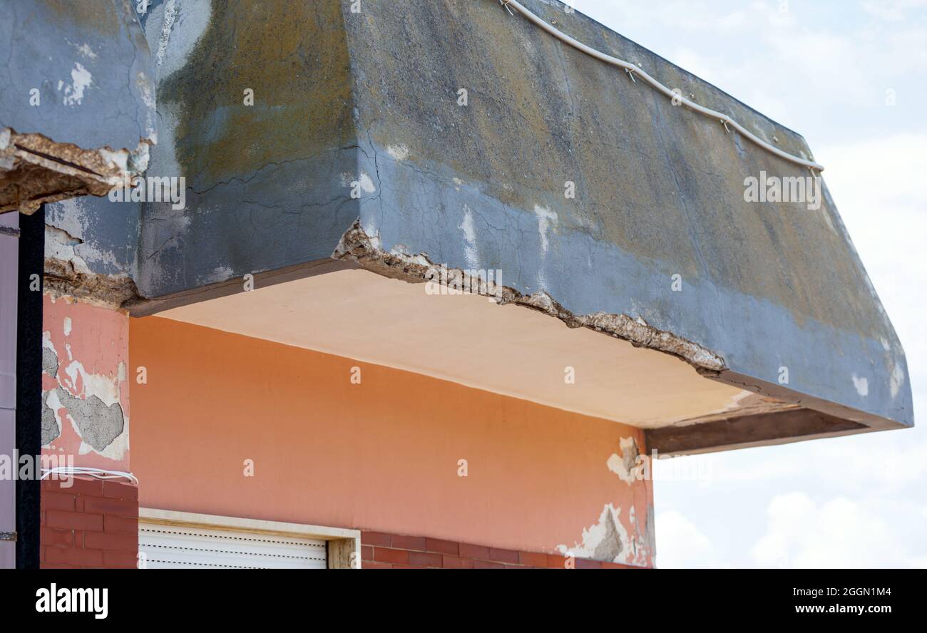 Wand mit rissigem Beton und rostigen Eisen, die renoviert werden müssen. Stockfoto