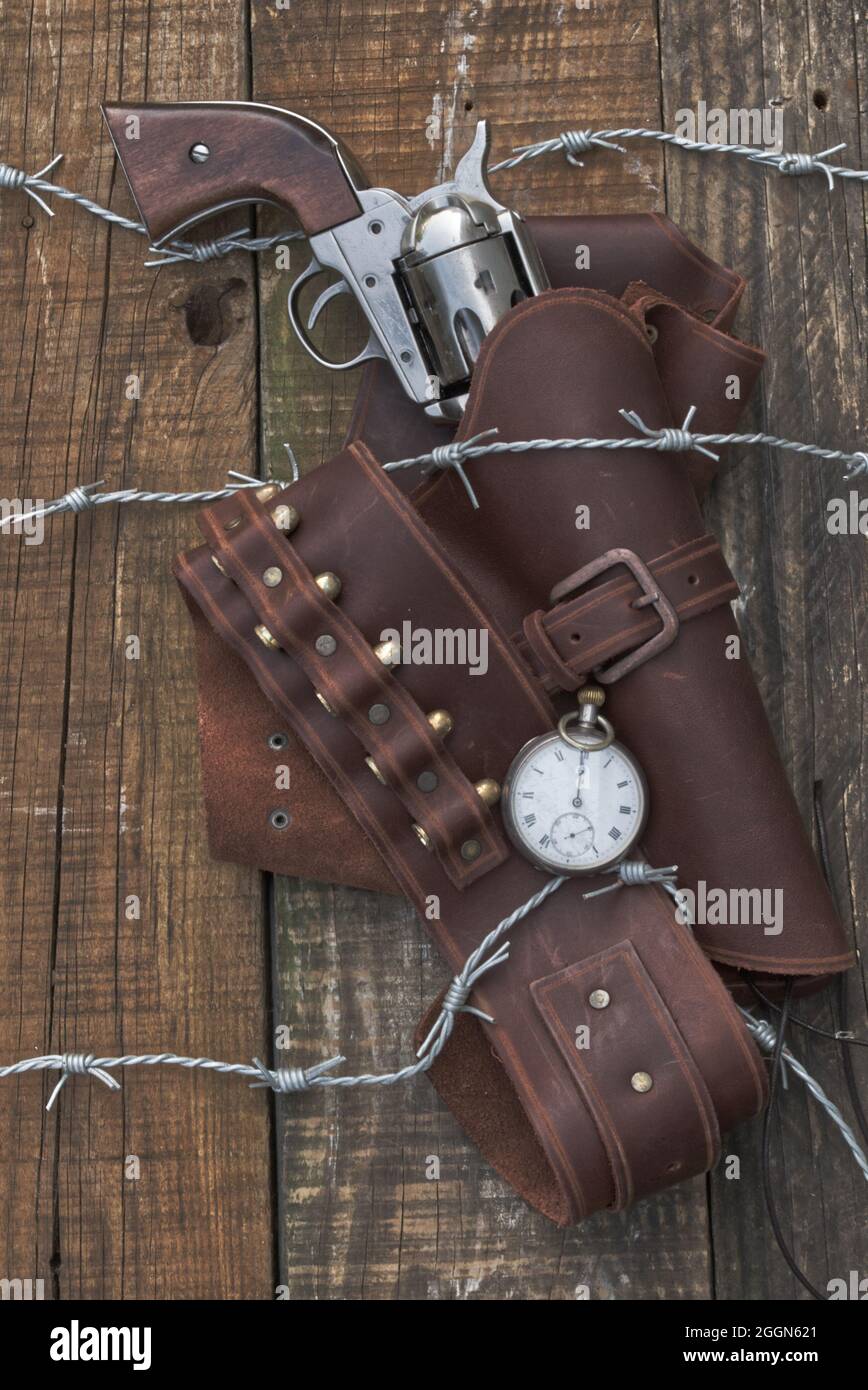 Cowboy 6 Shooter, Pistole mit Holster in Barbwire gefangen, auf Holzhintergrund. (Das alte westliche Buchcover)? Stockfoto