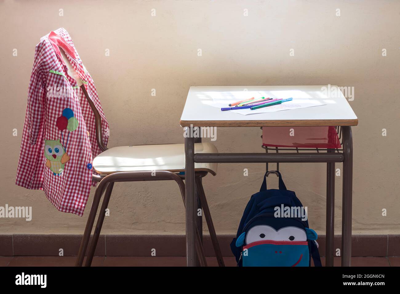 Foto des Schulmaterials eines Vorschulkindes.auf dem Foto sieht man eine Kinderschürze, einen Rucksack und einige Seiten mit Zeichnungen eines Kindes.Th Stockfoto