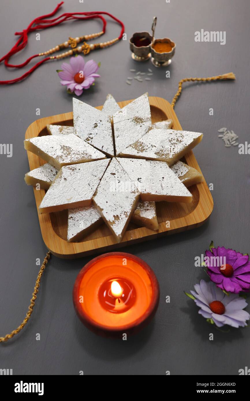 Indisches Festival Raksha bandhan. Rakhi-Thali mit Diya, Blumen und Tilak mit verschiedenen Süßigkeiten wie Gulab Jamun, Kaju katli und Churma Laddo. Stockfoto