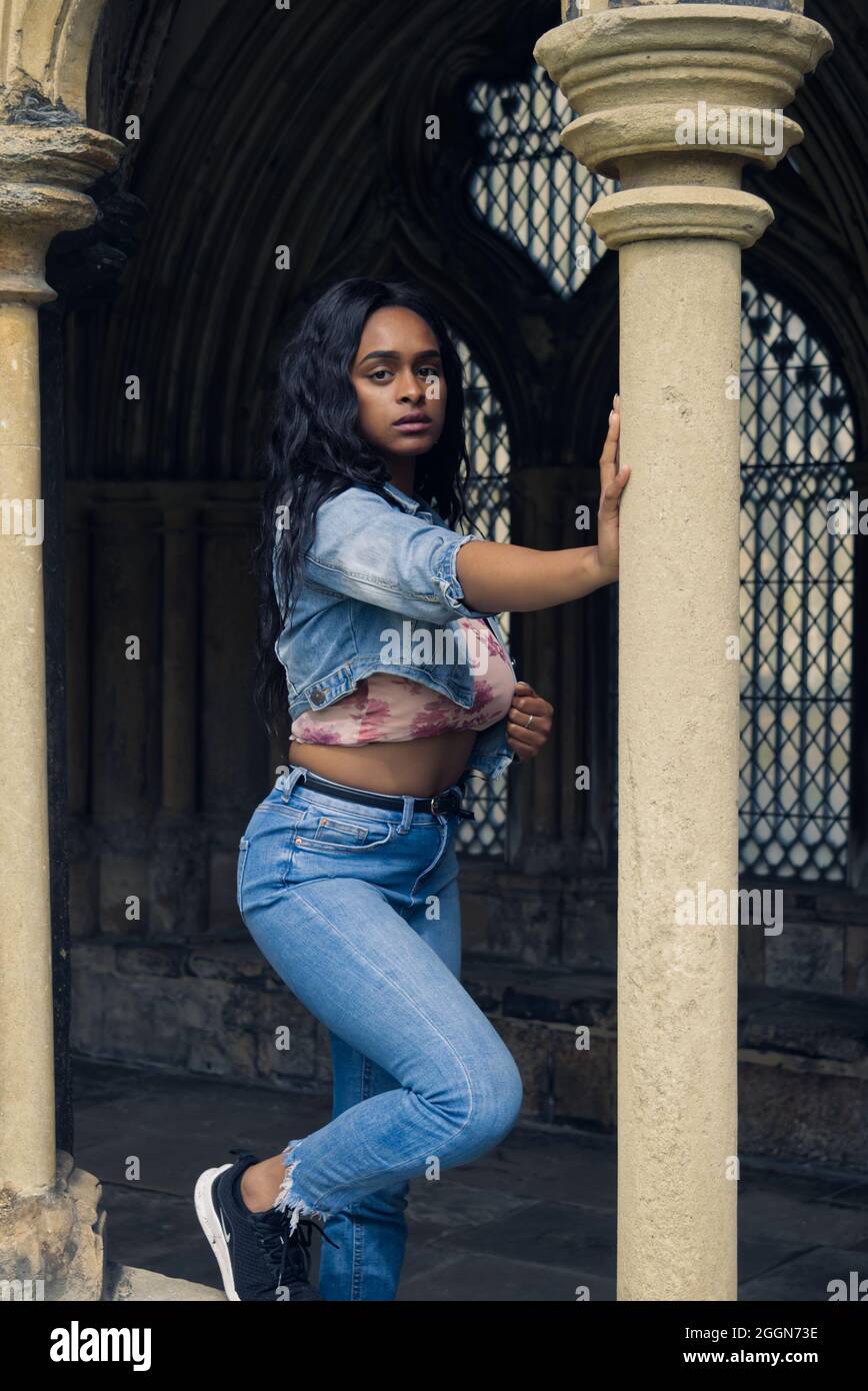 Junge, farbige Frau im Kloster einer Kathedrale in modernen Tüchern. Stockfoto