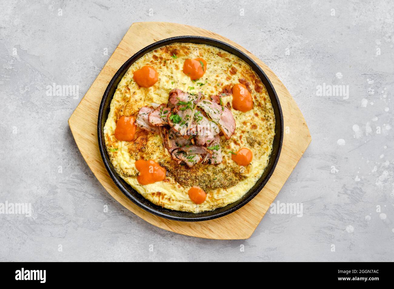 Blick von oben auf Eier mit Speck und Tomaten im Ofen in gusseiserner Pfanne gebacken Stockfoto