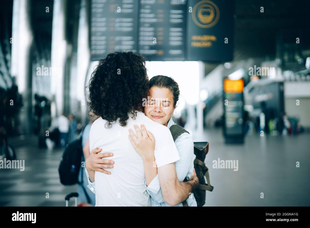 Das junge Familienpaar am Abflugbereich des Flughafens sagte Auf Wiedersehen oder hallo und umarmte sich mit einem Lächeln. Ankunft und Wiedersehen warten auf die Reise Stockfoto