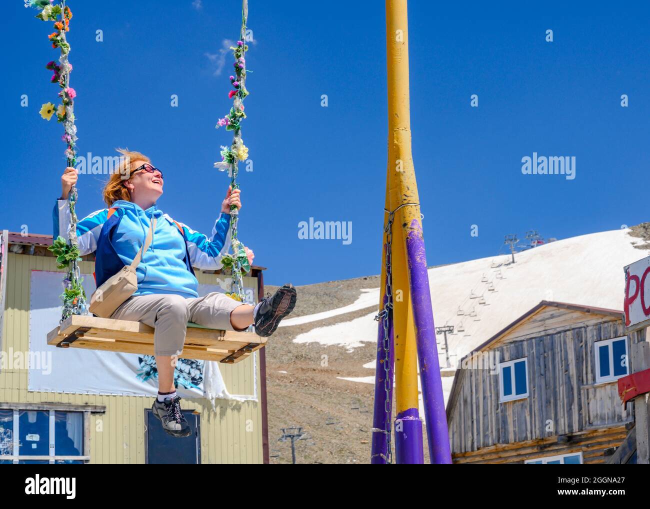 Eine Frau schwingt glücklich auf einer Schaukel hoch in den Bergen Stockfoto