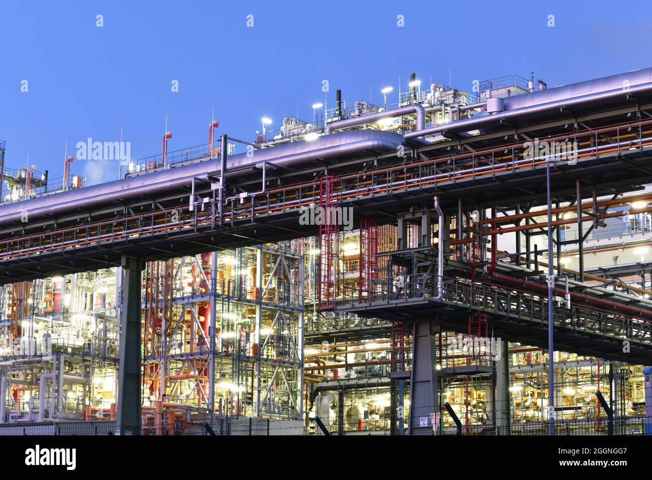 Chemische Fabrik in der Nacht mit Gebäuden, Rohrleitungen und Beleuchtung - Industrieanlage Stockfoto