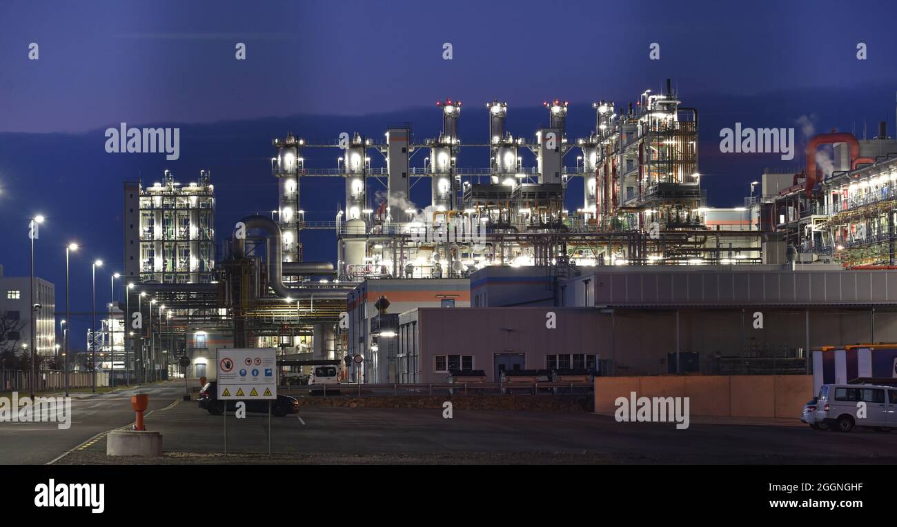 Chemische Fabrik in der Nacht mit Gebäuden, Rohrleitungen und Beleuchtung - Industrieanlage Stockfoto