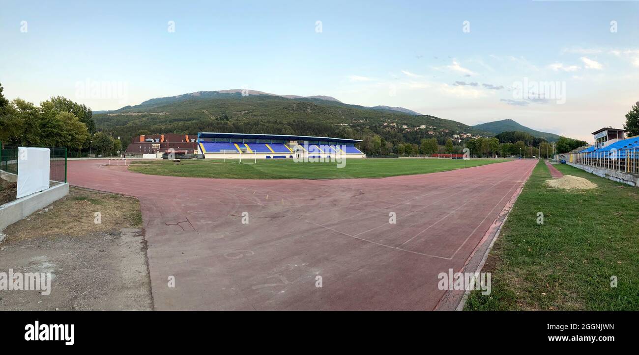 Panorama-Leichtathletik-Stadion mit Fußballplatz im Hintergrund Berge Stockfoto