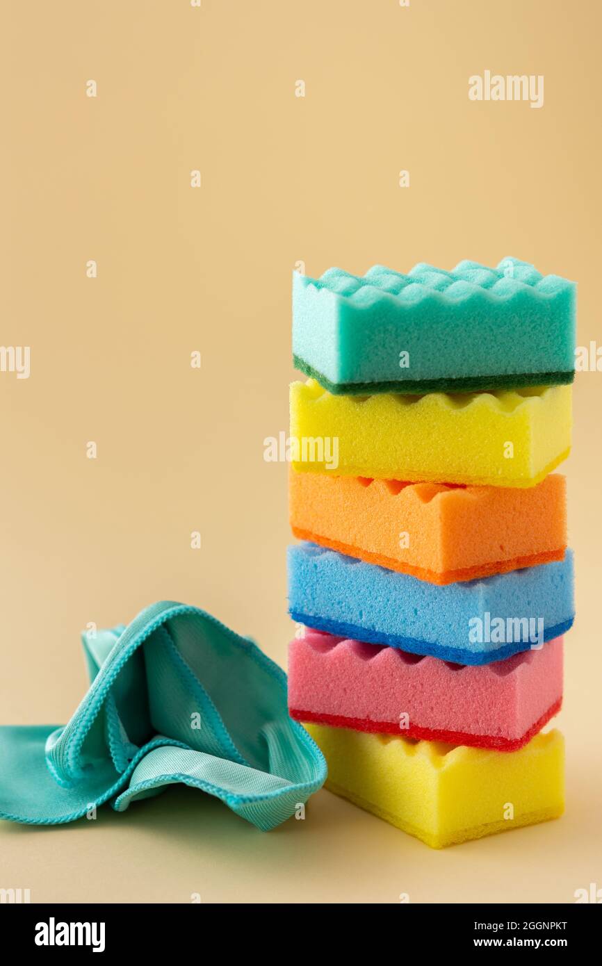 Stapel von bunten Spülschwämmen und Mikrofaser-Servietten auf neutralem beigen Hintergrund, Küchenhaushalt und Reinigungskonzept Stockfoto