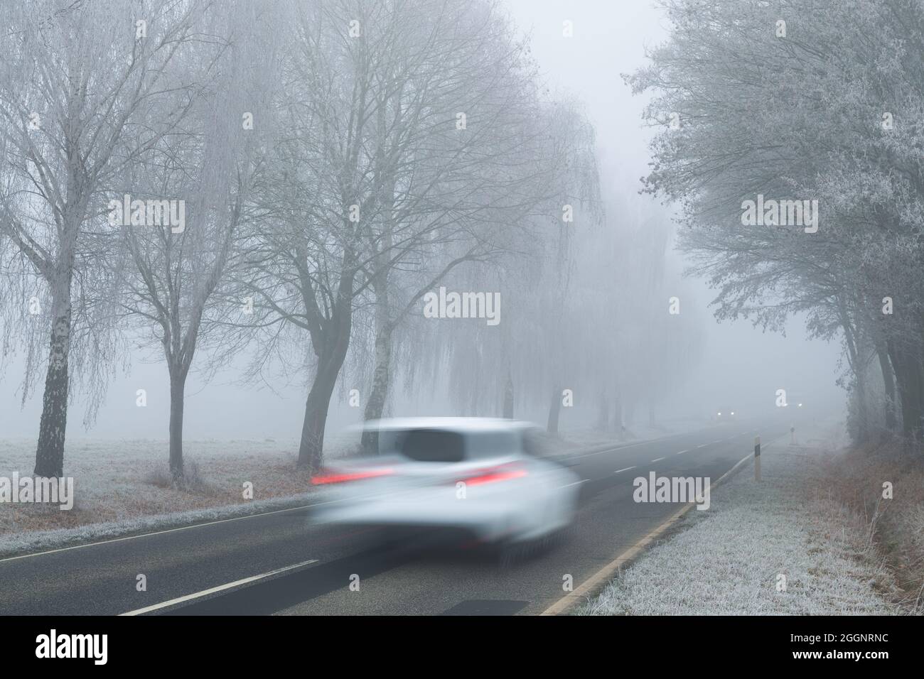 Verschwommenes Auto in Bewegung auf der Straße im Winter während eines nebligen Tages Stockfoto