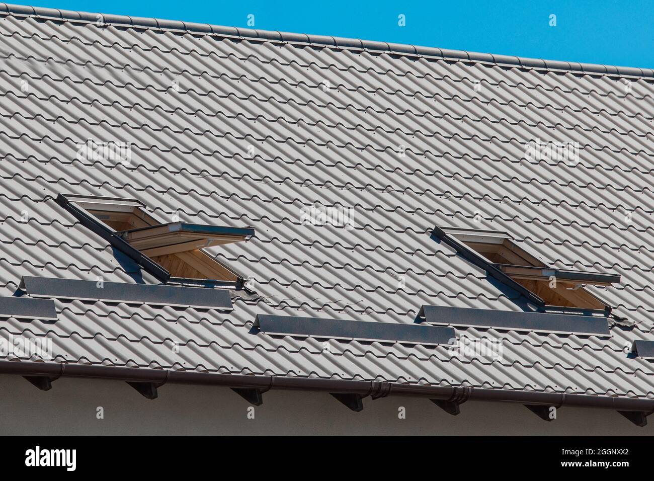 Modernes Design des Daches des Hauses mit offener Fensterarchitektur gegen den blauen Himmel. Stockfoto