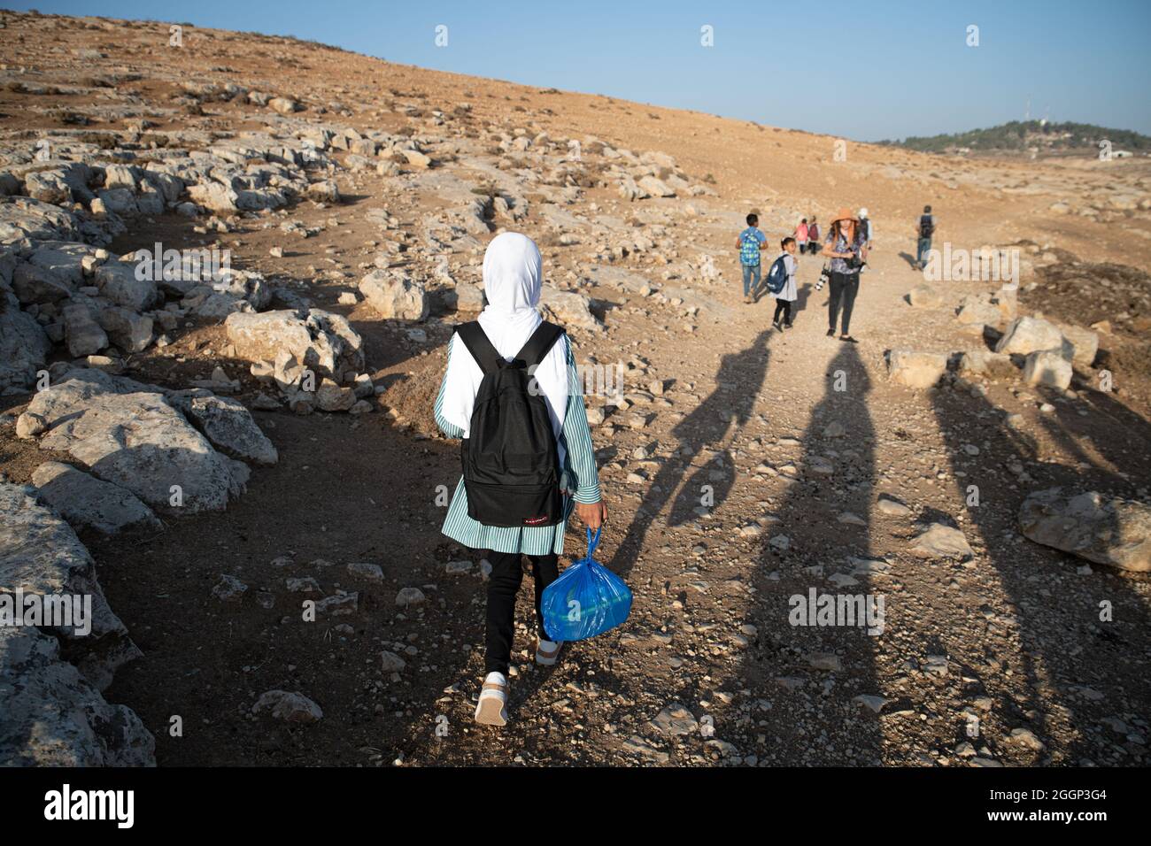 Seit 2004 gehen die Kinder aus dem Dorf Tuba zur Schule im nahegelegenen Dorf at-Tuwani, 2.6 km entfernt - während sie von einem jüdischen Aktivisten und einem Fahrzeug der israelischen Streitkräfte begleitet werden, um sie vor gewalttätigen Angriffen der religiösen jüdischen Siedler aus dem illegalen Außenposten der Maon Farm zu schützen, die auf dem Weg zur Schule gefunden wird. Palästina/Israel, südlich von Hebron. August 2021. (Foto: Matan Golan/Sipa USA) Quelle: SIPA USA/Alamy Live News Stockfoto