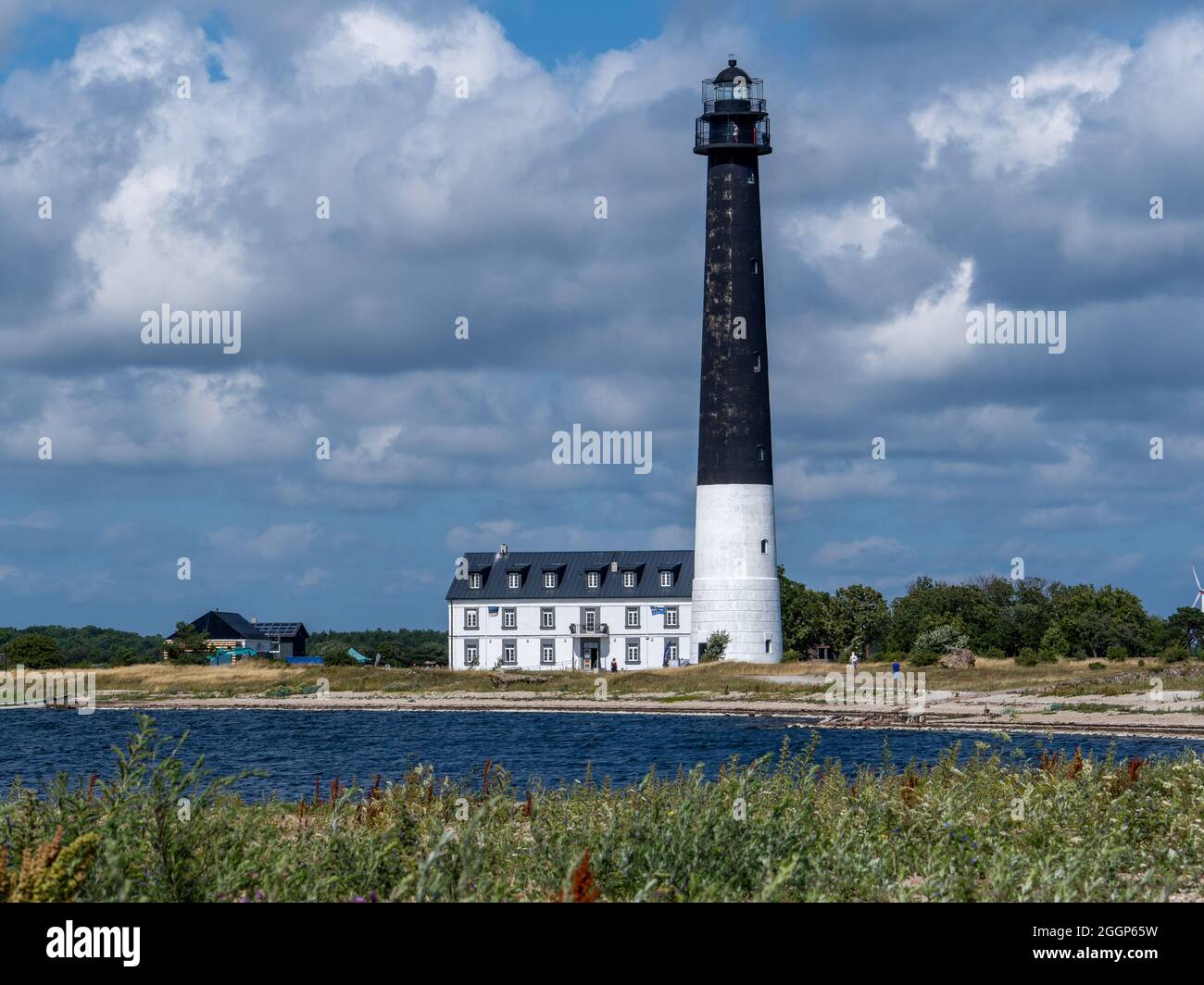 Estland, Insel Saaremaa. Am Ufer des Sõrve-Horns erhebt sich ein weißer Leuchtturm hoch über dem Boden. Sommer, sonnendurchflutete Aussicht auf das Meer des Leuchtturms Stockfoto