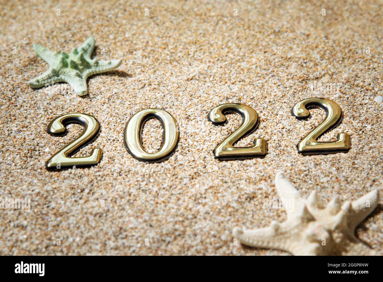 Konzept Strandsaison 2021. Goldene Zahlen 2022 und Seesterne auf dem Sand am Meer. Stockfoto