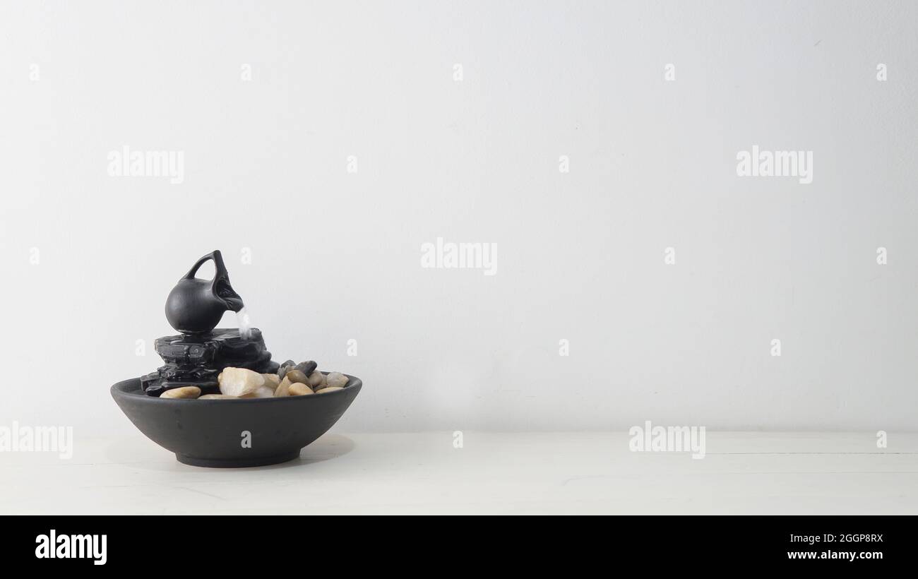 Blick auf einen Zen-Brunnen auf einem weißen Holztisch mit weißem Hintergrund Stockfoto