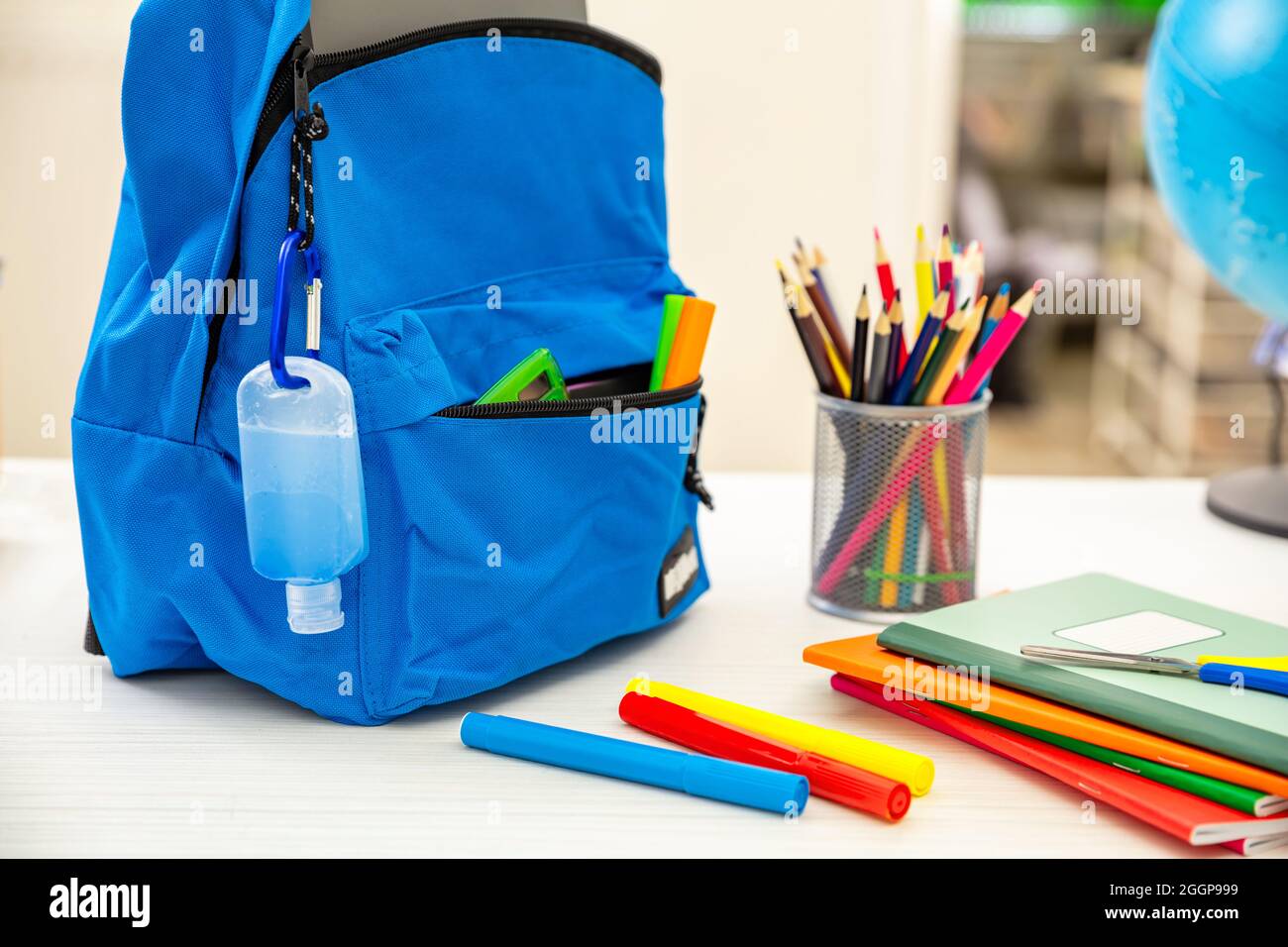 Schule COVID 19 Tage. Coronavirus-Schutzmaßnahme, Händedesinfektionsgel und Rucksack für Schultaschen auf dem Schülerschreibtisch, Nahaufnahme, Stockfoto