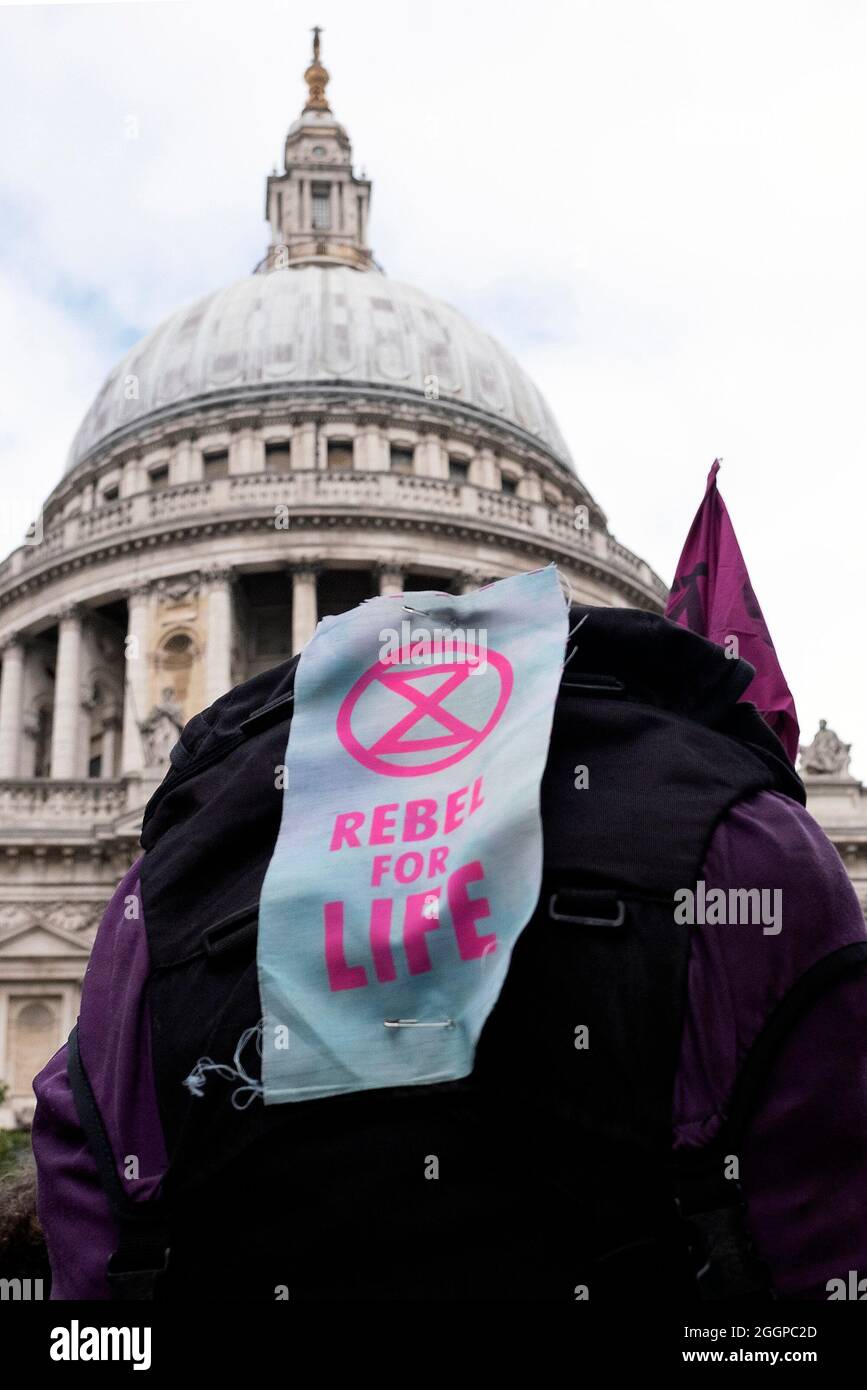Ein Plakat mit der Aufschrift „REBEL FOR LIFE“ ist an einem Rucksack der Protestierenden festgeklafft, während die Protestierenden am 2. September 2021 von der Tate Modern über die Millennium Bridge während des Extinction Protestes des Rebellions gegen die Massenernagbarung am elften Tag ihrer Impossible Rebellion-Proteste in London, Großbritannien, marschieren. Stockfoto