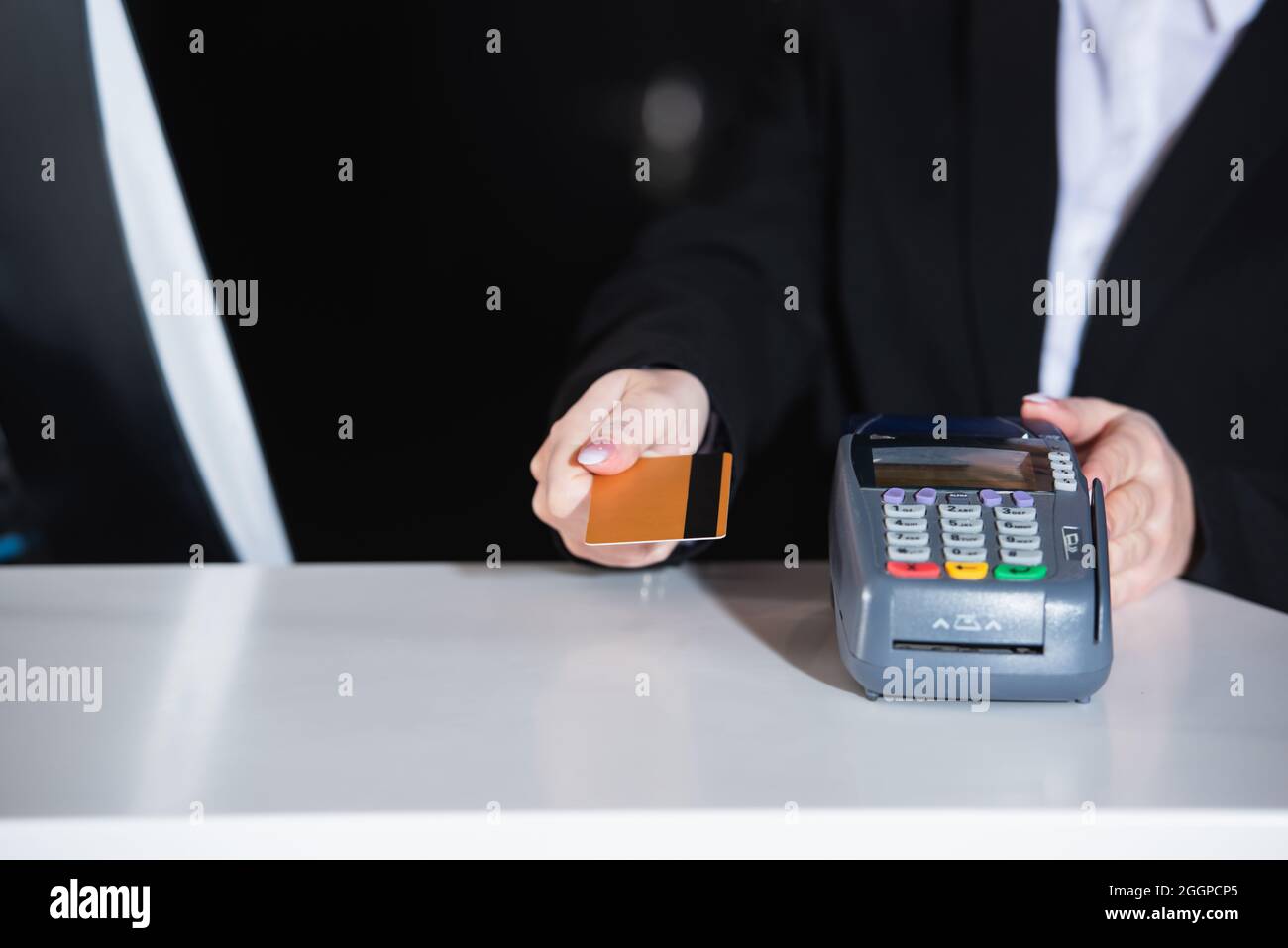 Beschnittene Ansicht des Administrators, der die Kreditkarte in der Nähe des Zahlungsterminals im Hotel hält Stockfoto