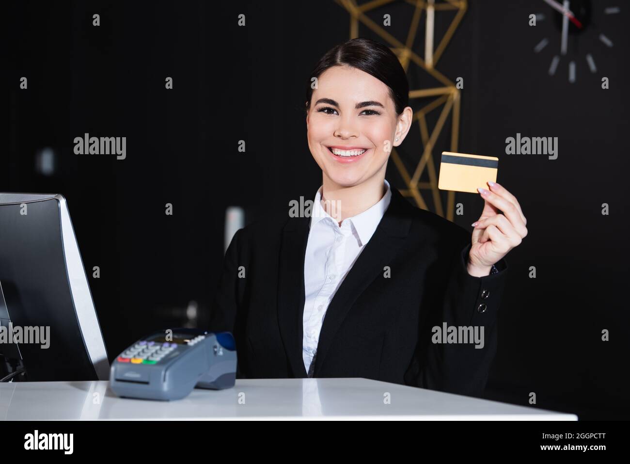 Glücklicher Verwalter, der die Kreditkarte in der Nähe des Zahlungsterminals im Hotel hält Stockfoto