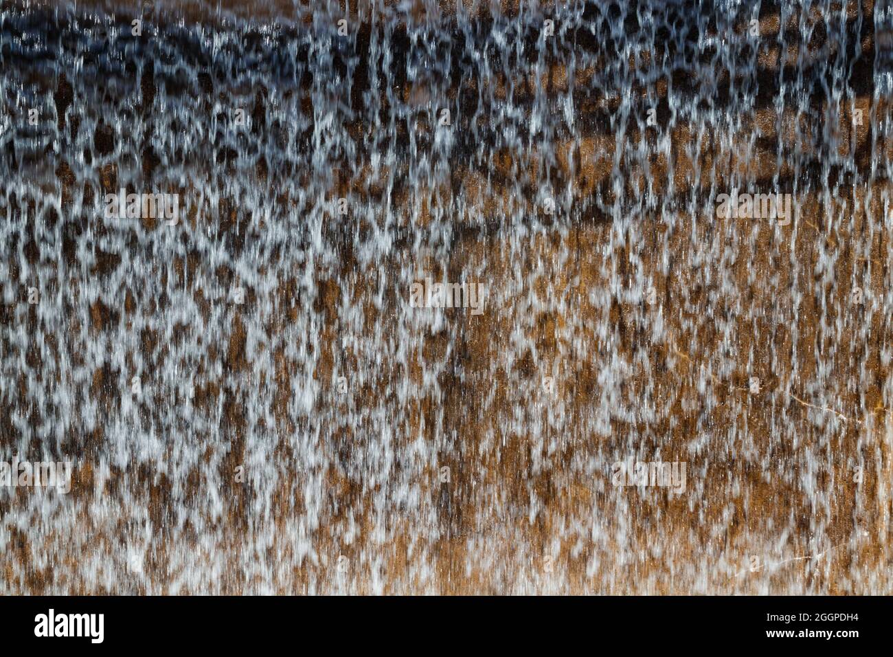 Textur eines fließenden Wasserfalls an der Wand. Stockfoto