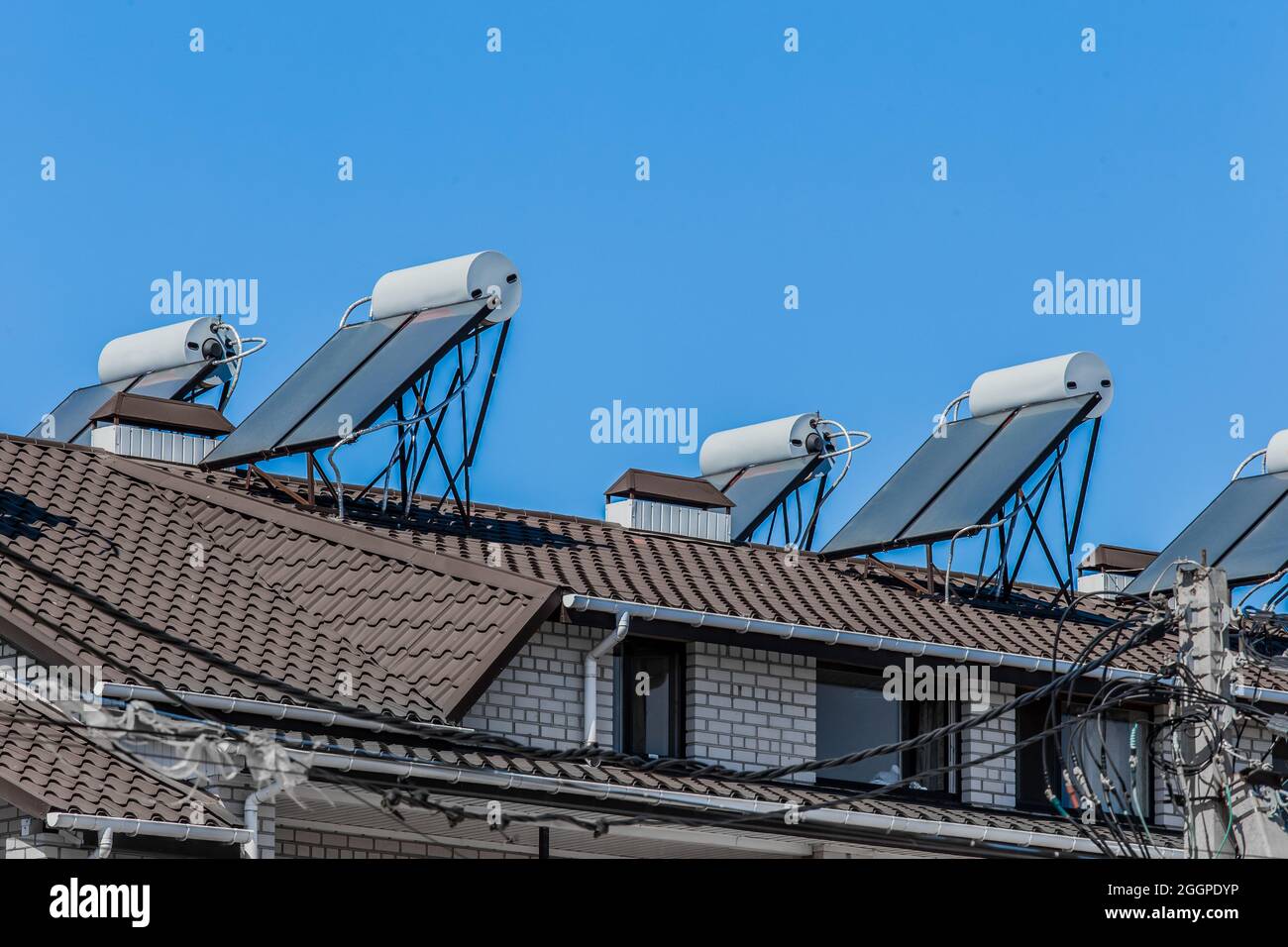 Thermische Sonnenkollektoren und Warmwasserbereiter alternative Technologien der Wasserheizung auf dem Dach des Hotels gegen den blauen Himmel im Freien. Stockfoto