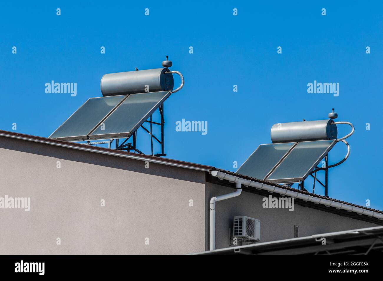 Thermische Sonnenkollektoren und Warmwasserbereiter alternative Technologie der Wasserheizung auf dem Dach des Hauses gegen den blauen Himmel. Stockfoto