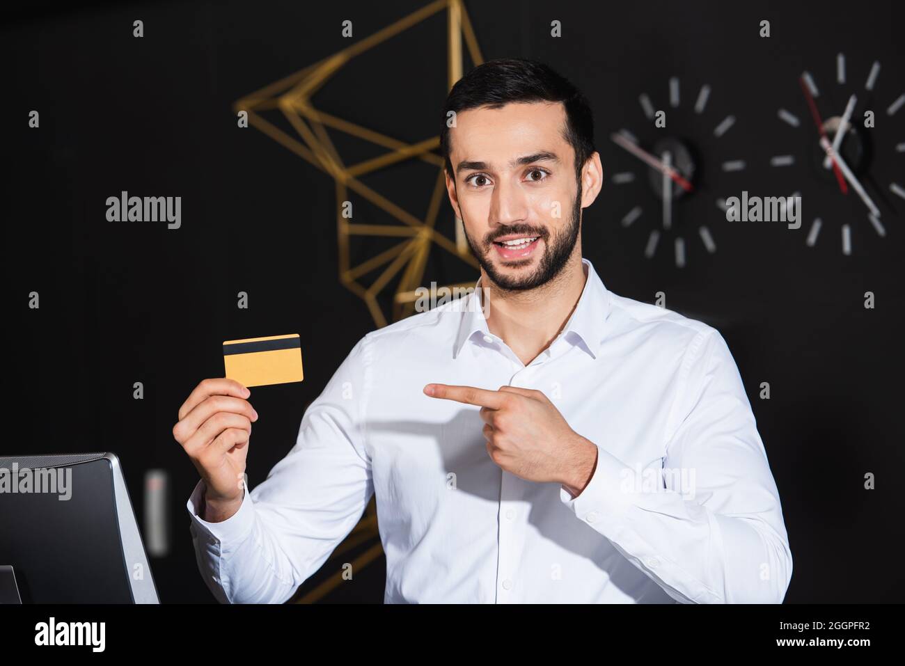 Der bärtige Rezeptionist zeigte auf die Kreditkarte und lächelte im Hotel Stockfoto