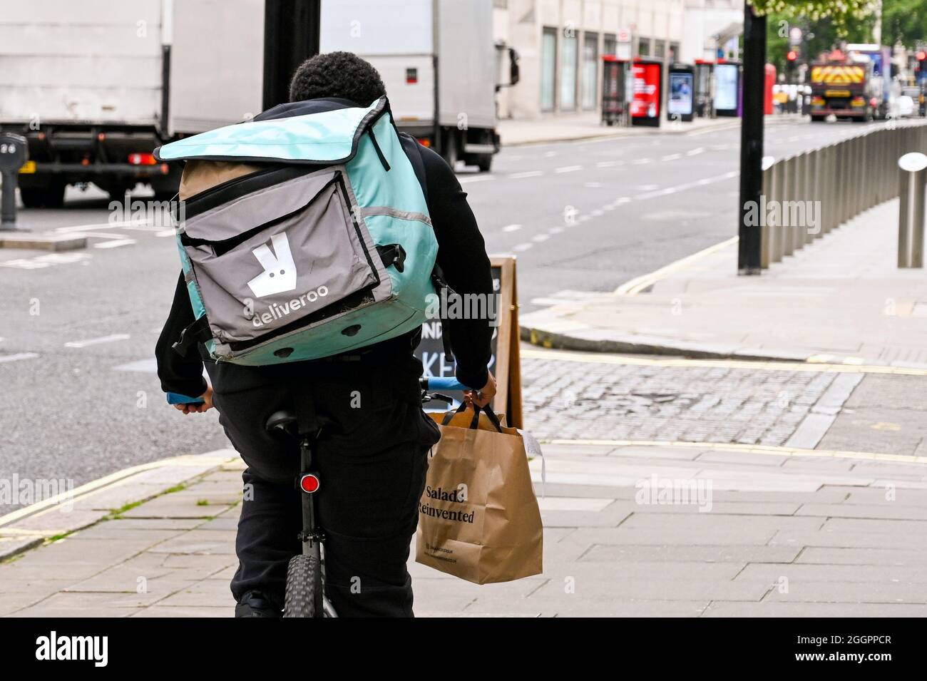 London, England - 2021. August: Person, die für Deliveroo arbeitet, auf dem Fahrrad fährt und einen Auftrag liefert Stockfoto