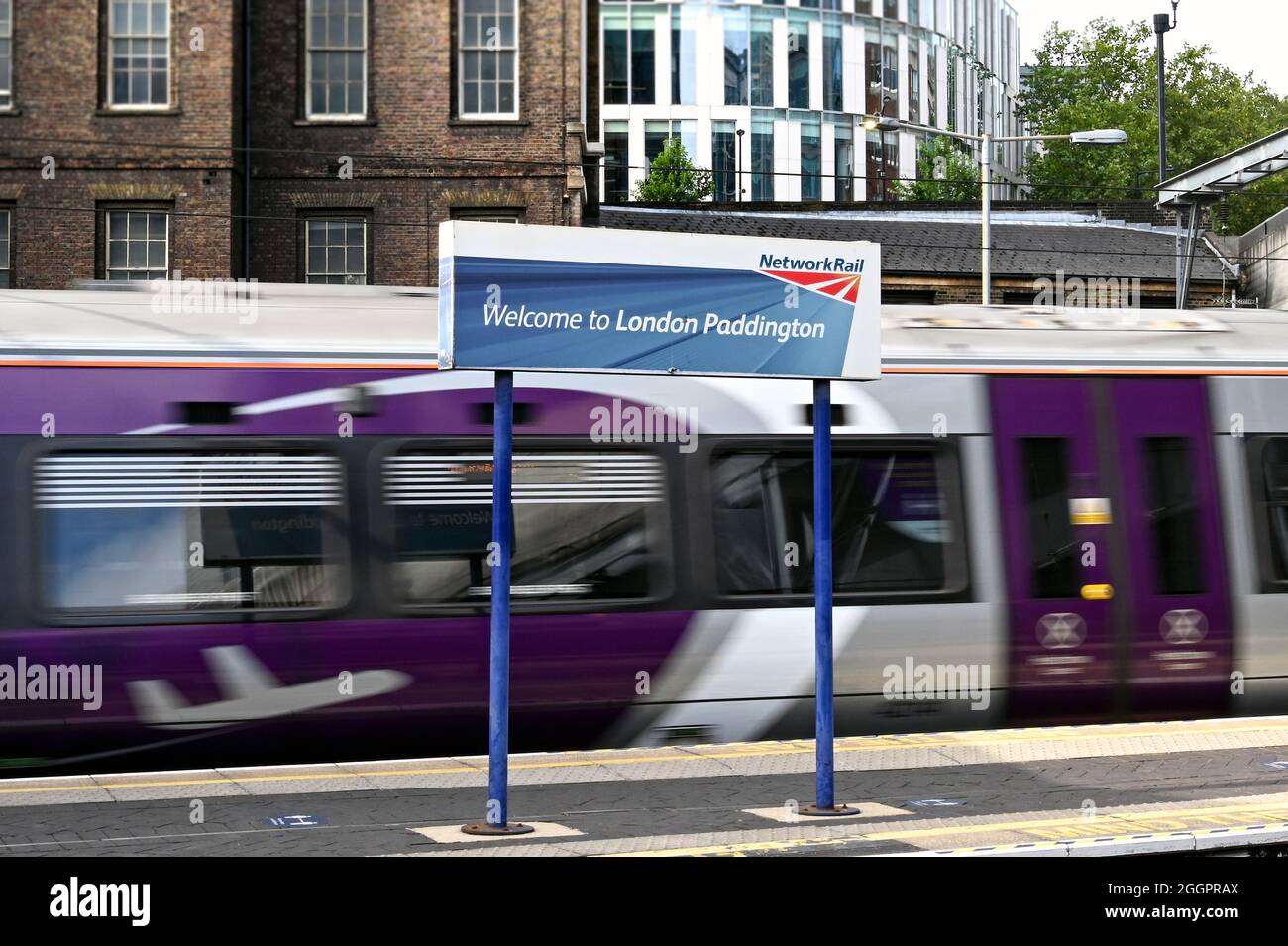 London, England - 2021. August: Unterschreiben Sie auf einem Bahnsteig am Bahnhof Paddington in London. Im Hintergrund ist ein Heathrow Express Zug mit Bewegungsunschärfe Stockfoto