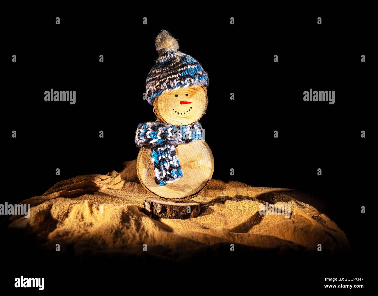 Handgefertigter Schneemann aus Holz mit Häkelhut und Schal vor schwarzem Hintergrund Stockfoto