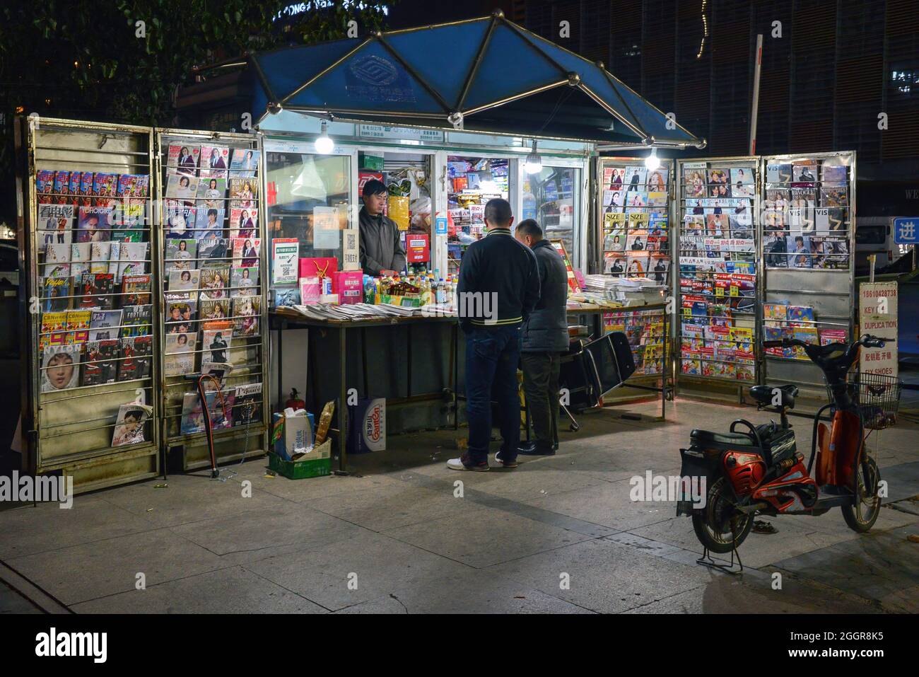 Peking, China - 11. November 2017: An einem Zeitungsstand im Freien in Peking kaufen die Menschen nachts ein. Stockfoto