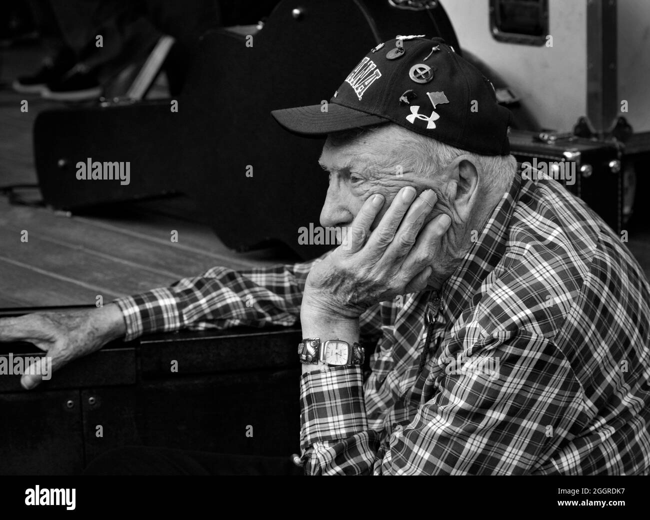 Ein älterer Mann sitzt mit, während er Menschen bei einem Musikkonzert im Freien in Santa Fe, New Mexico, tanzen sieht. Stockfoto