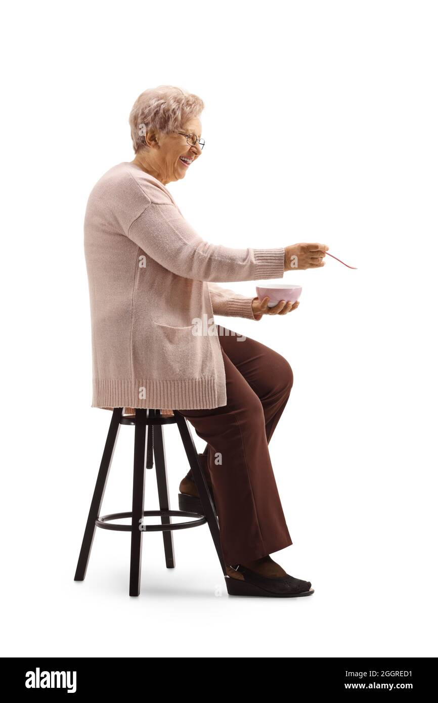 Ältere Frau sitzt und Löffel Fütterung isoliert auf weißem Hintergrund Stockfoto
