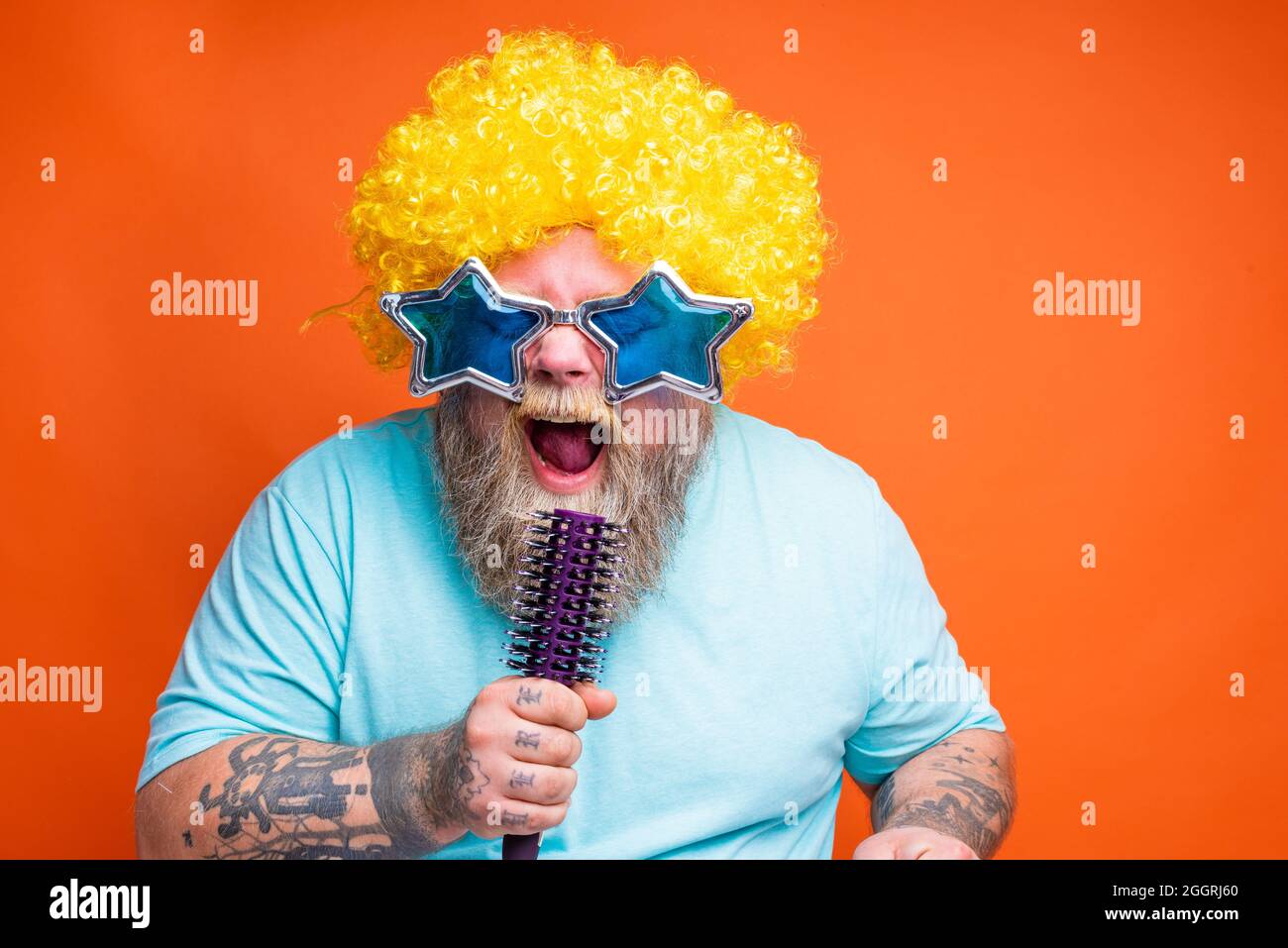 Ein fetter Mann mit Bart, Tattoos und Sonnenbrillen singt ein Lied Stockfoto