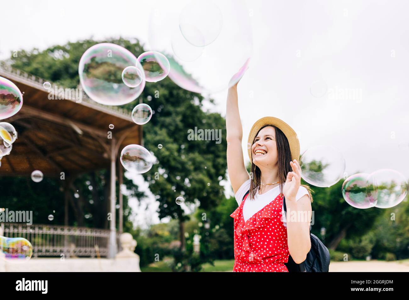 Junge hispanische Frau hat Spaß beim Spielen mit Seifenblasen im Stadtpark Stockfoto