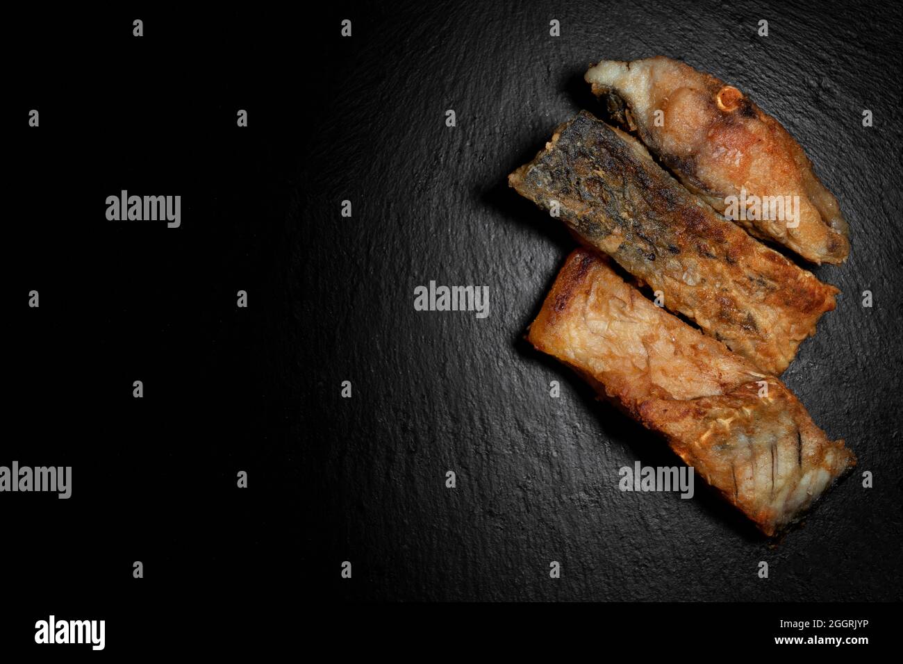 Drei gebratene Karpfenfische auf schwarzem Hintergrund Stockfoto