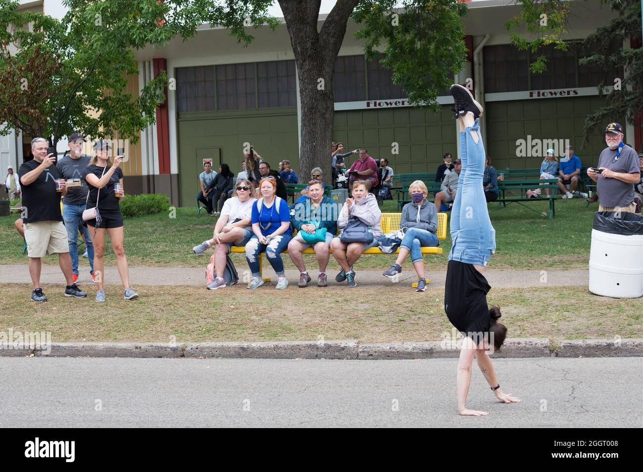Eine junge Frau, die auf ihren Händen steht, während eine Menschenmenge auf der Minnesota State Fair zuschaut. Stockfoto